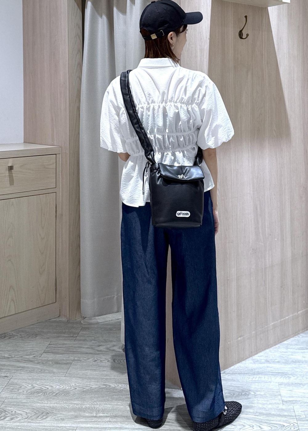 ブラック系のショルダーバッグ、ブラック系のパンプス、ブルー系のデニムパンツを着用したレディースの夏コーディネートの9枚目の写真