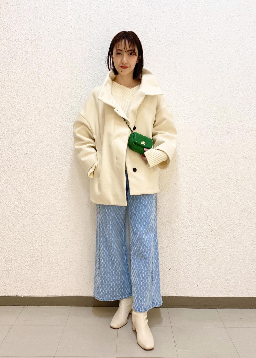 ホワイト系のステンカラーコート、グリーン系のショルダーバッグ、ホワイト系のニット/セーターを着用したレディースの冬コーディネートの3枚目の写真