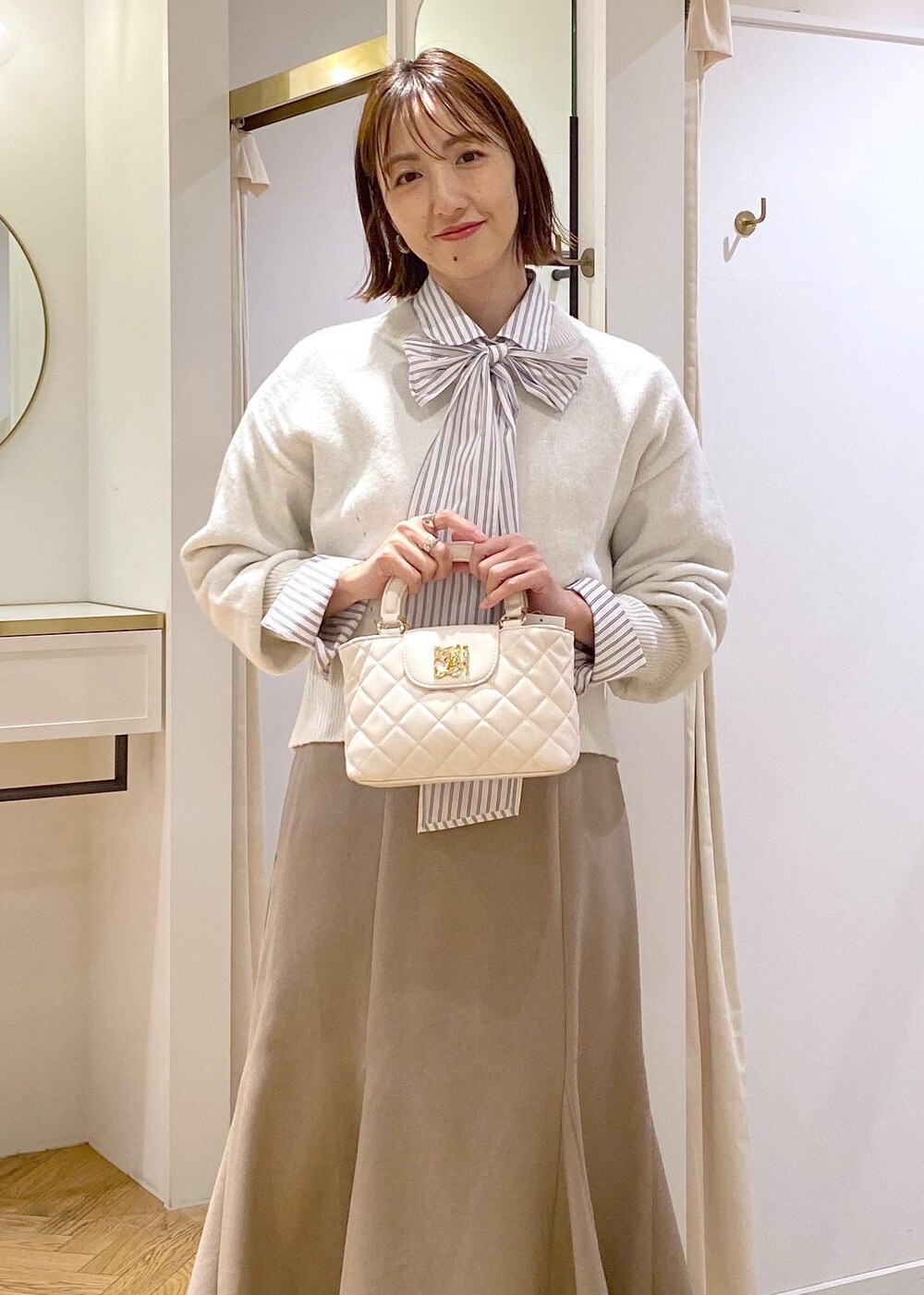 ブラック系のパンプス、ベージュ系のスカート、ホワイト系のシャツ/ブラウスを着用したレディースの冬コーディネートの6枚目の写真