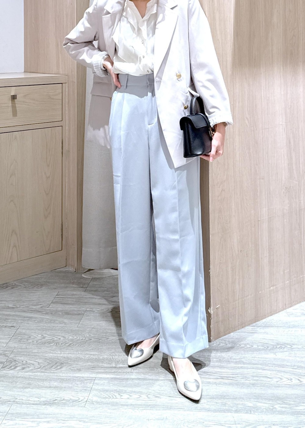 ブラック系のショルダーバッグ、ブルー系のスラックス、ベージュ系のテーラードジャケットを着用したレディースの春コーディネートの7枚目の写真