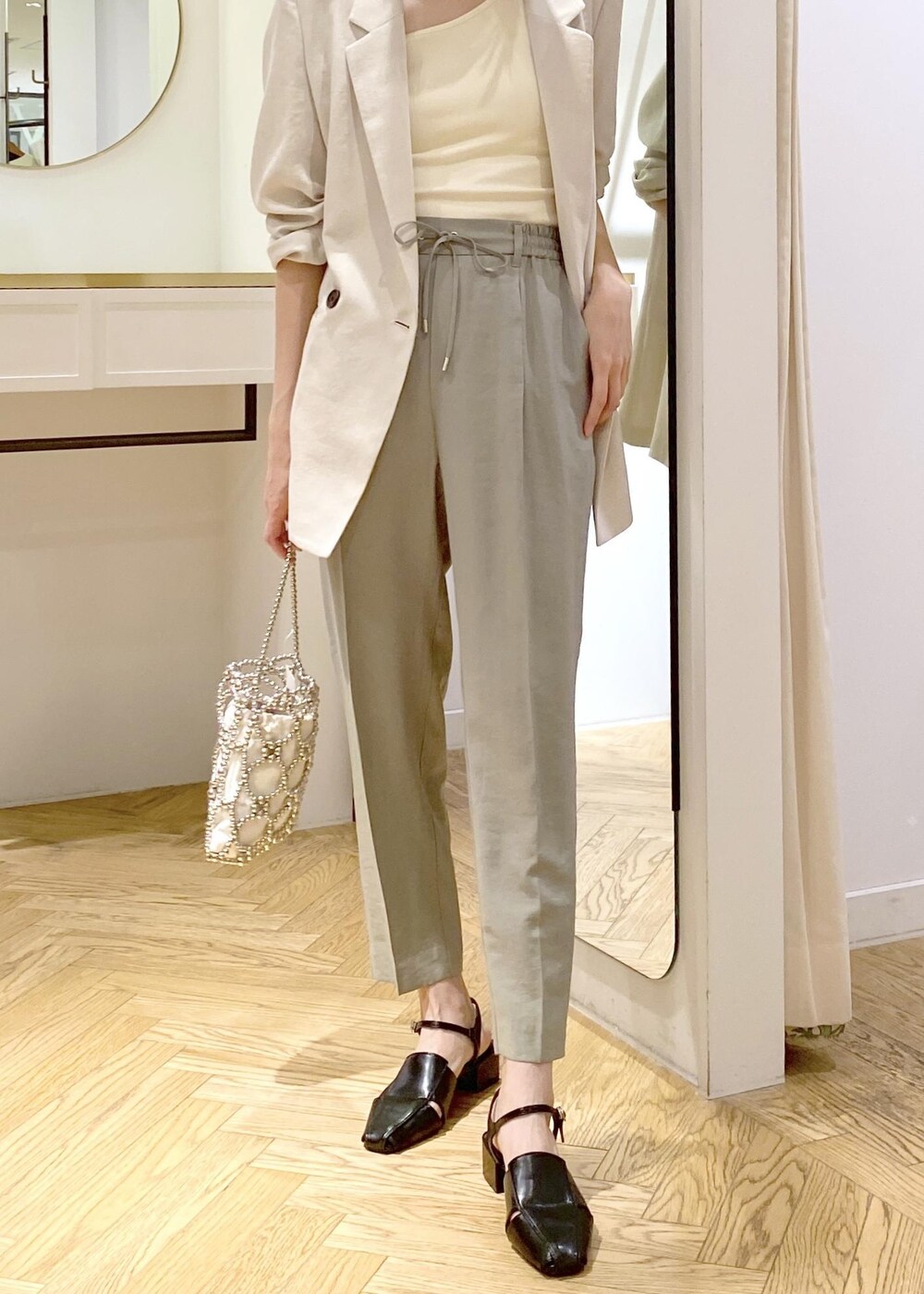 ホワイト系のタンクトップ、ブラック系のサンダル、グリーン系のスラックスを着用したレディースの春コーディネートの4枚目の写真