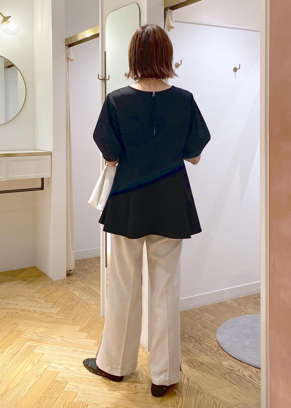 ホワイト系のショルダーバッグ、ホワイト系のスラックス、ブラック系のバレエシューズを着用したレディースの秋コーディネートの3枚目の写真