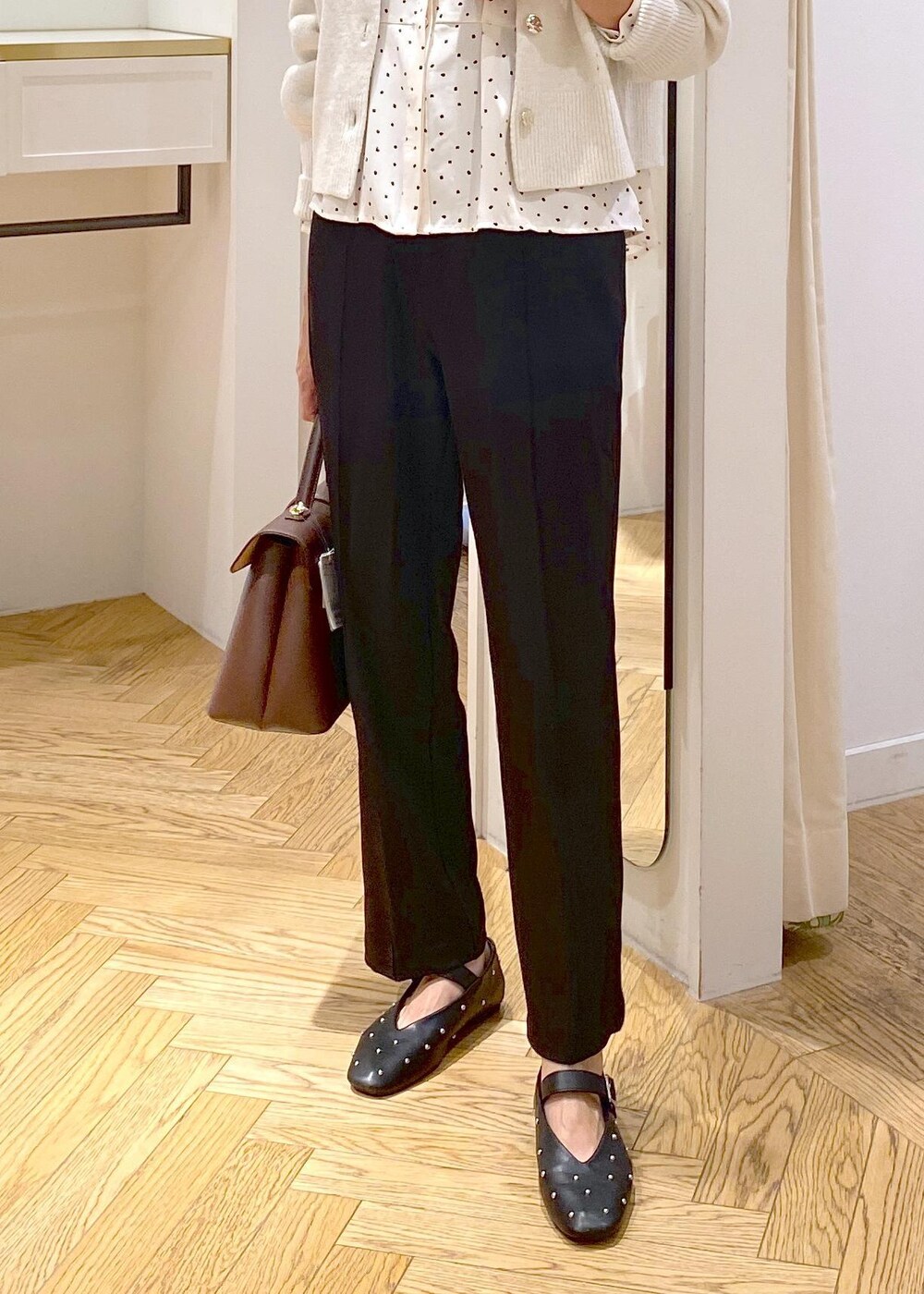 ブラウン系のハンドバッグ、ブラック系のバレエシューズ、ブラック系のスラックスを着用したレディースの秋コーディネートの5枚目の写真