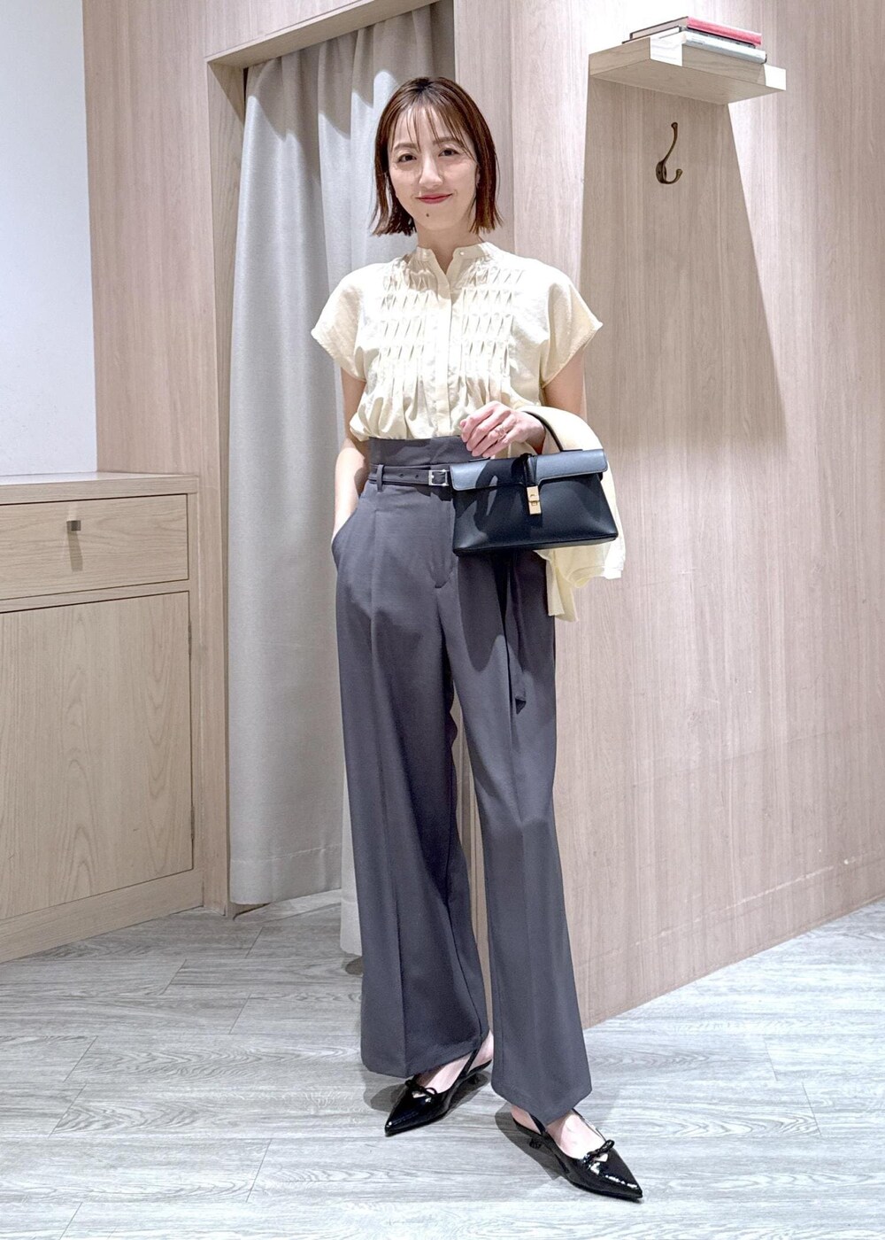 ブラック系のショルダーバッグ、ブラック系のパンプス、ホワイト系のカーディガン/ボレロを着用したレディースの夏コーディネートの2枚目の写真