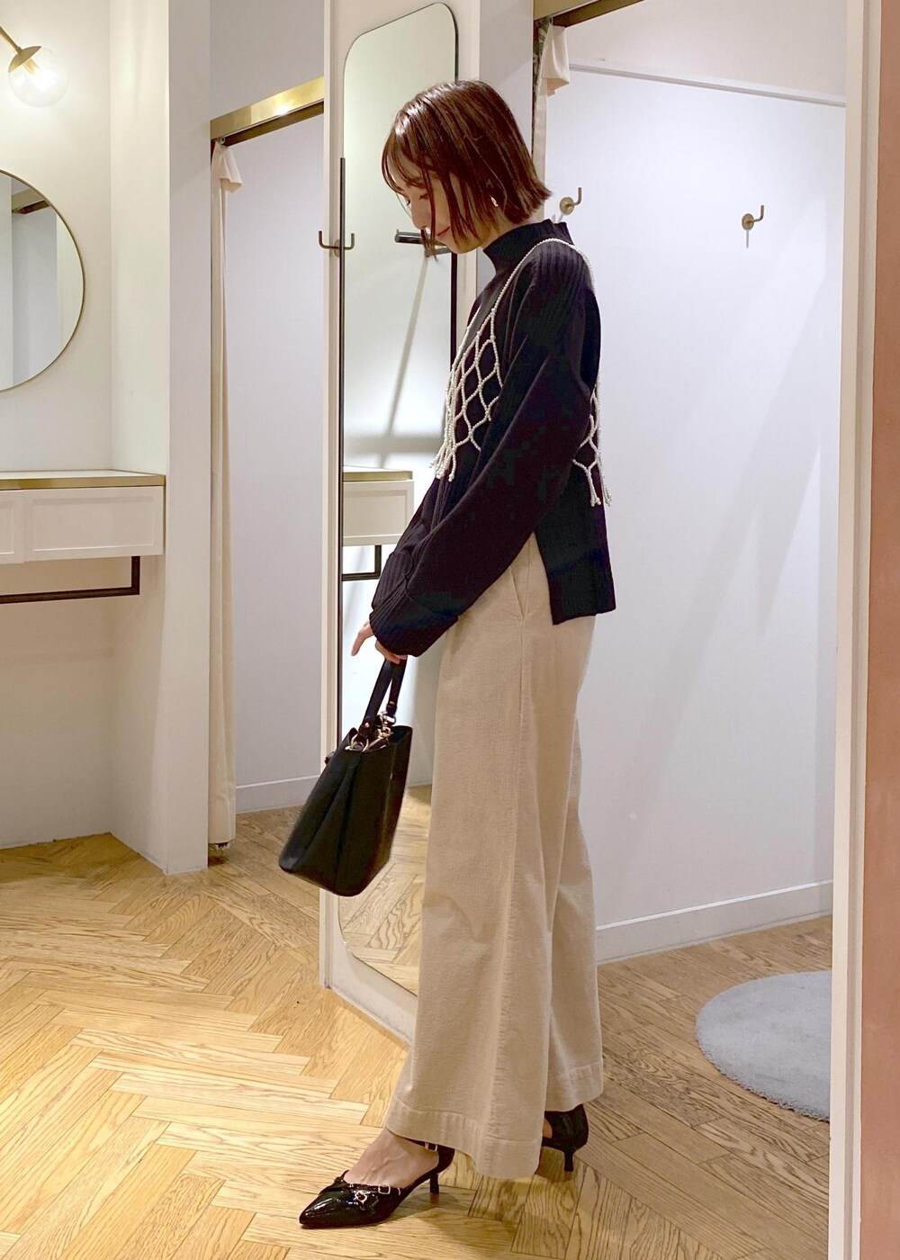 ブラック系のショルダーバッグ、ホワイト系のキャミソール、ベージュ系のスラックスを着用したレディースの秋コーディネートの2枚目の写真