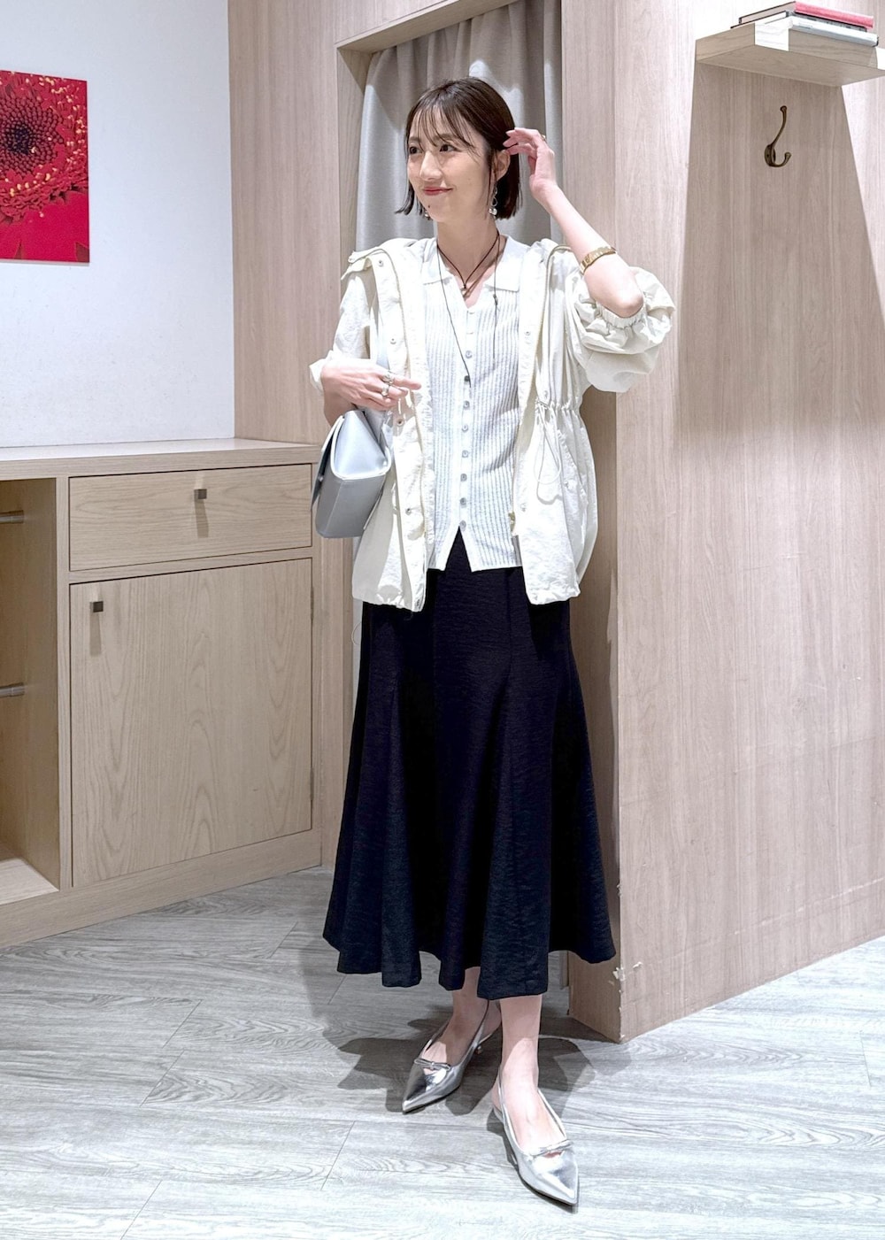 シルバー系のパンプス、ブラック系のスカート、ホワイト系のカーディガン/ボレロを着用したレディースの春コーディネートの2枚目の写真