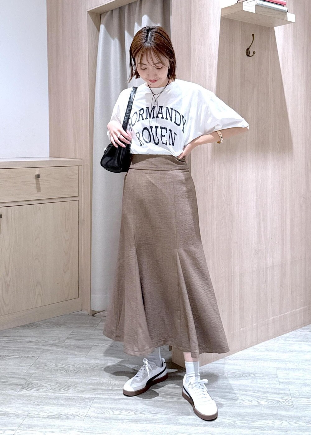 グリーン系のスカート、ホワイト系のTシャツ/カットソー、ブラック系のハンドバッグを着用したレディースの春コーディネートの4枚目の写真