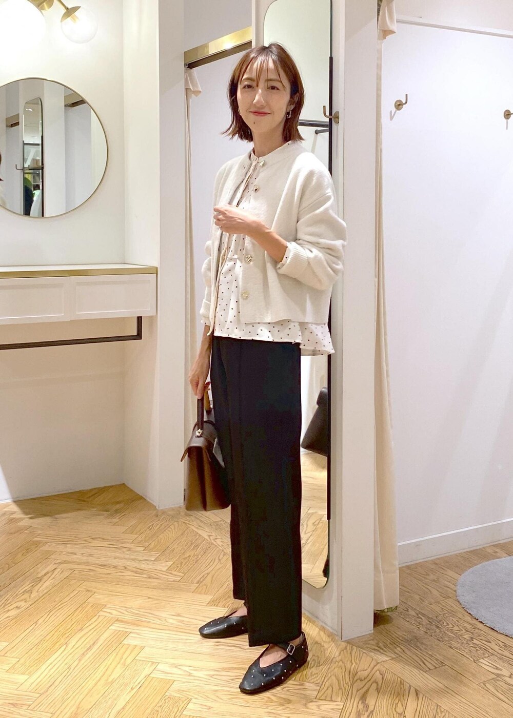 ブラウン系のハンドバッグ、ブラック系のバレエシューズ、ブラック系のスラックスを着用したレディースの秋コーディネートの2枚目の写真