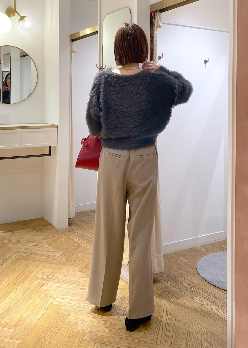 レッド系のトートバッグ、ベージュ系のスラックス、グレー系のカーディガン/ボレロを着用したレディースの冬コーディネートの4枚目の写真