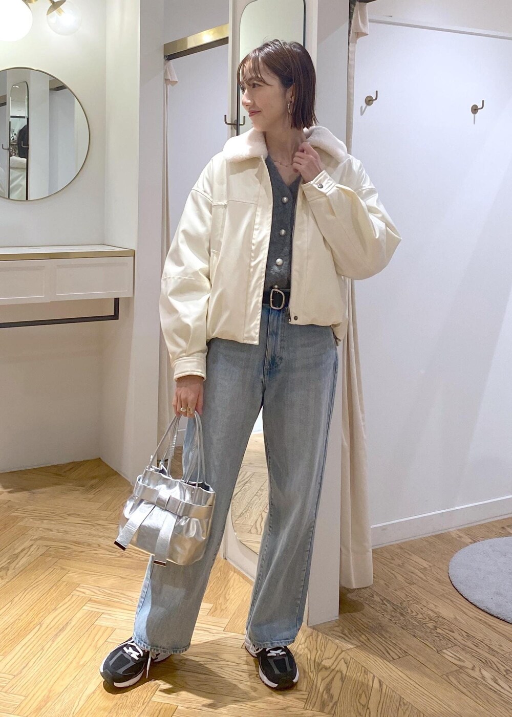 シルバー系のショルダーバッグ、ブルー系のデニムパンツ、グレー系のカーディガン/ボレロを着用したレディースの冬コーディネートの3枚目の写真