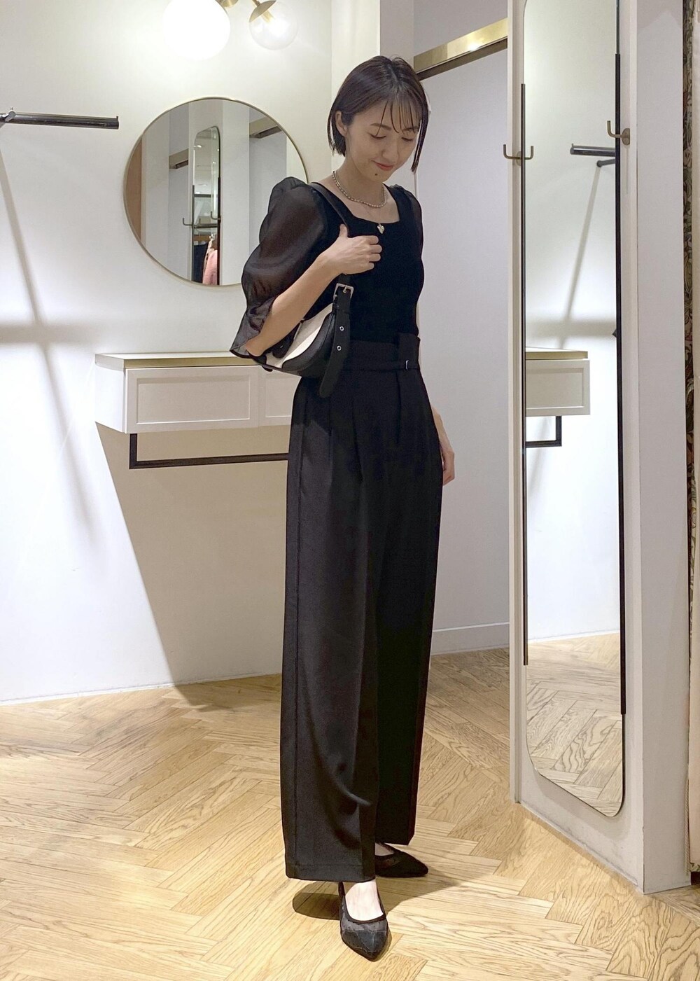 ブラック系のパンプス、ブラック系のショルダーバッグ、ブラック系のスラックスを着用したレディースの夏コーディネートの7枚目の写真