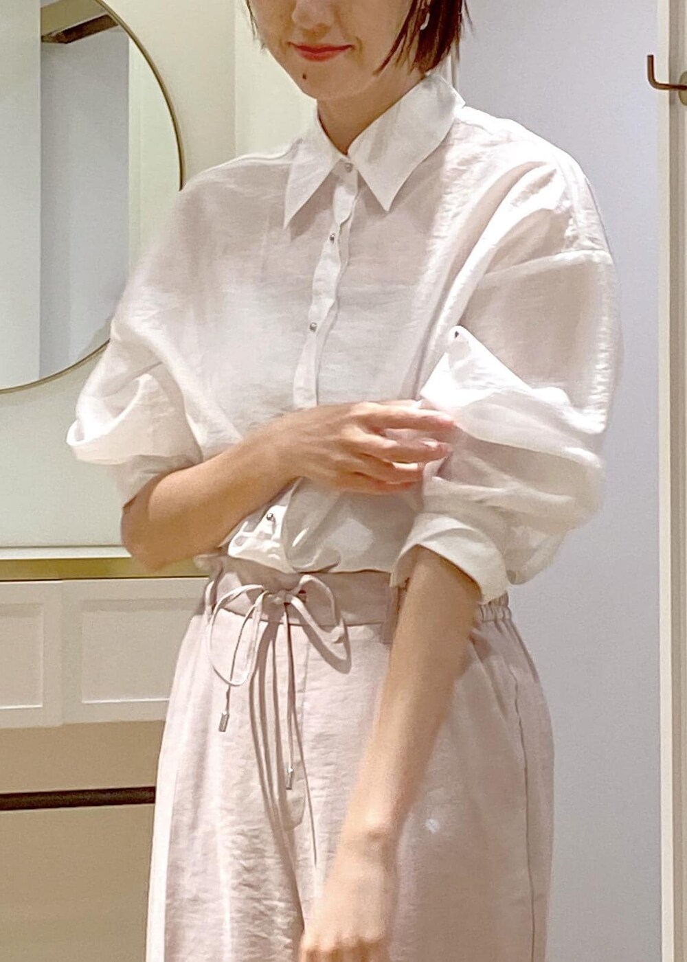 ブラック系のパンプス、ブラック系のハンドバッグ、ホワイト系のスラックスを着用したレディースの夏コーディネートの6枚目の写真