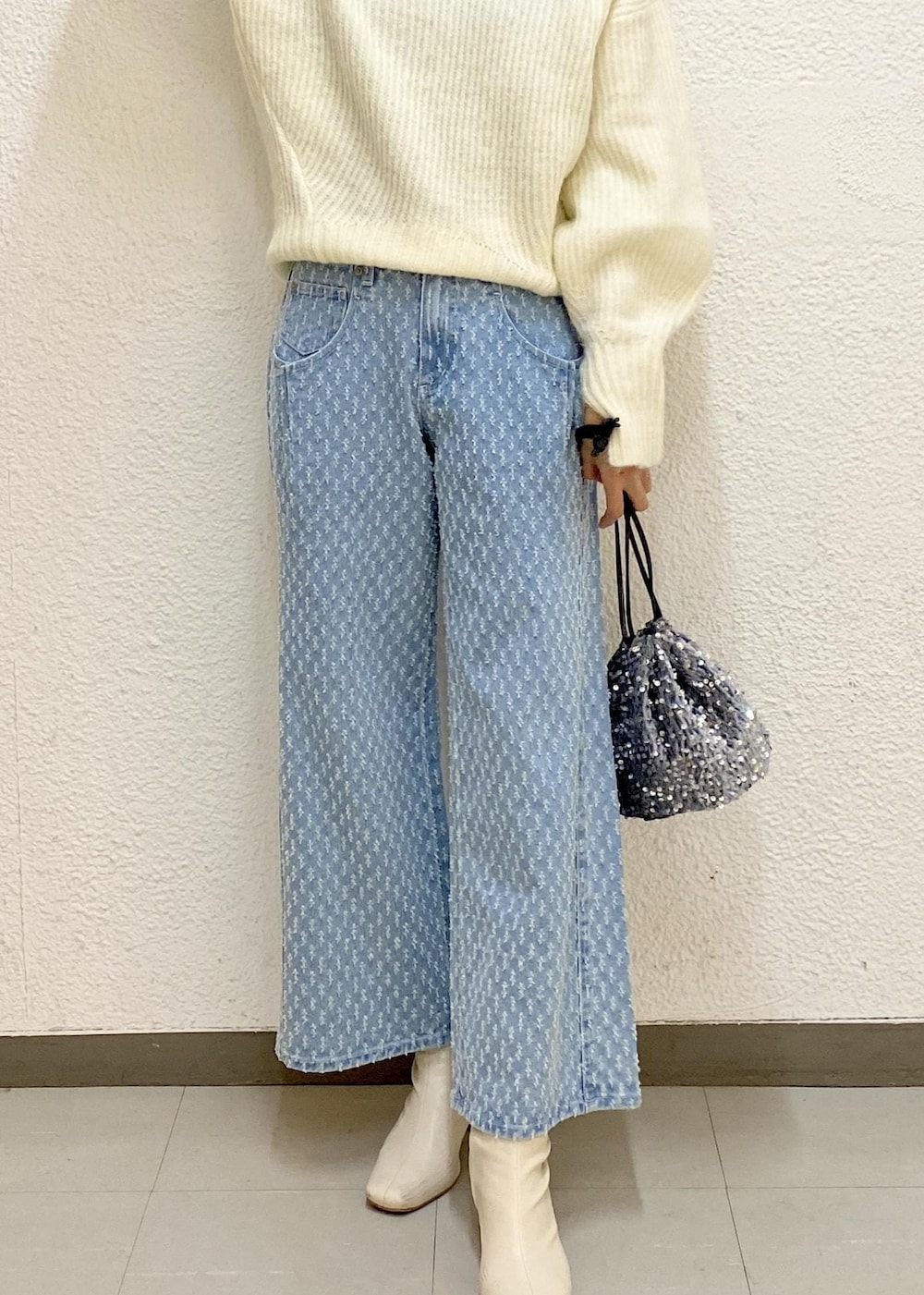 シルバー系のハンドバッグ、ホワイト系のニット/セーター、ブルー系のデニムパンツを着用したレディースの冬コーディネートの3枚目の写真