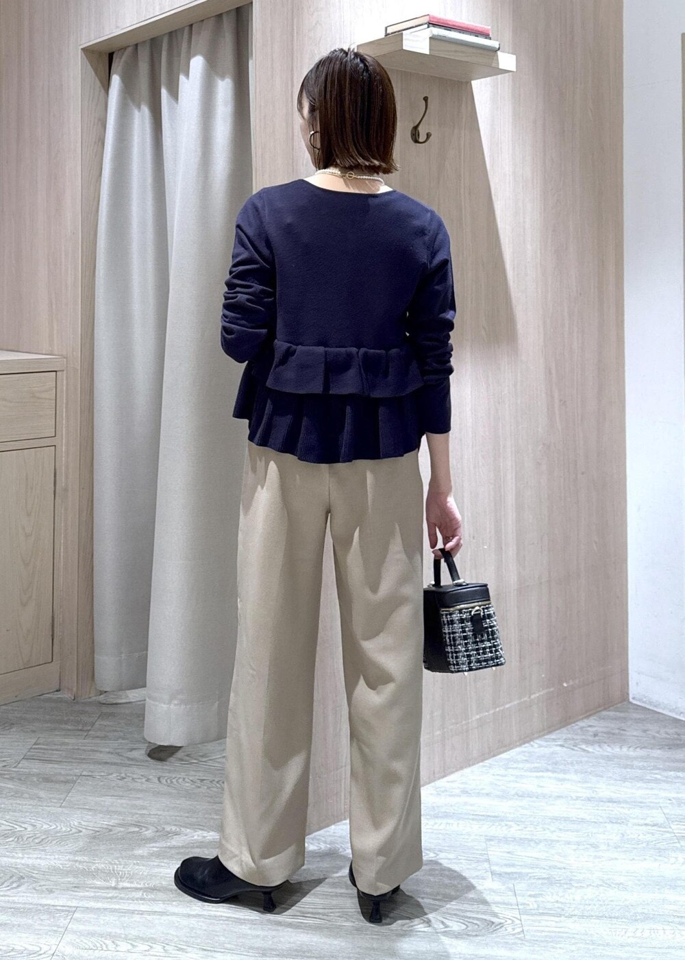 ベージュ系のスラックス、その他のハンドバッグ、ブルー系のカーディガン/ボレロを着用したレディースの冬コーディネートの3枚目の写真