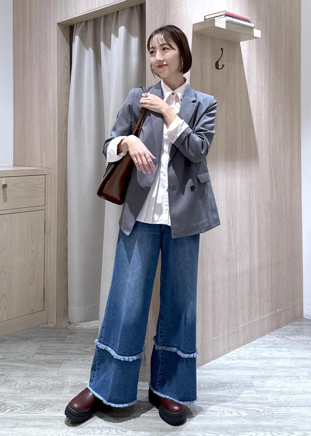 ブラウン系のブーツ、ピンク系のシャツ/ブラウス、ブルー系のデニムパンツを着用したレディースの秋コーディネートの2枚目の写真