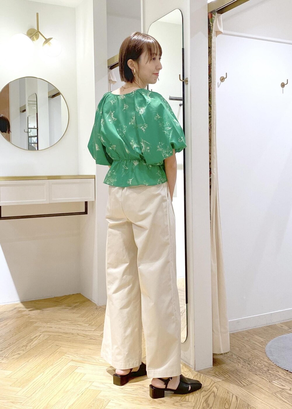 ホワイト系のスラックス、ブラック系のサンダル、ホワイト系のキャミソールを着用したレディースの春コーディネートの2枚目の写真