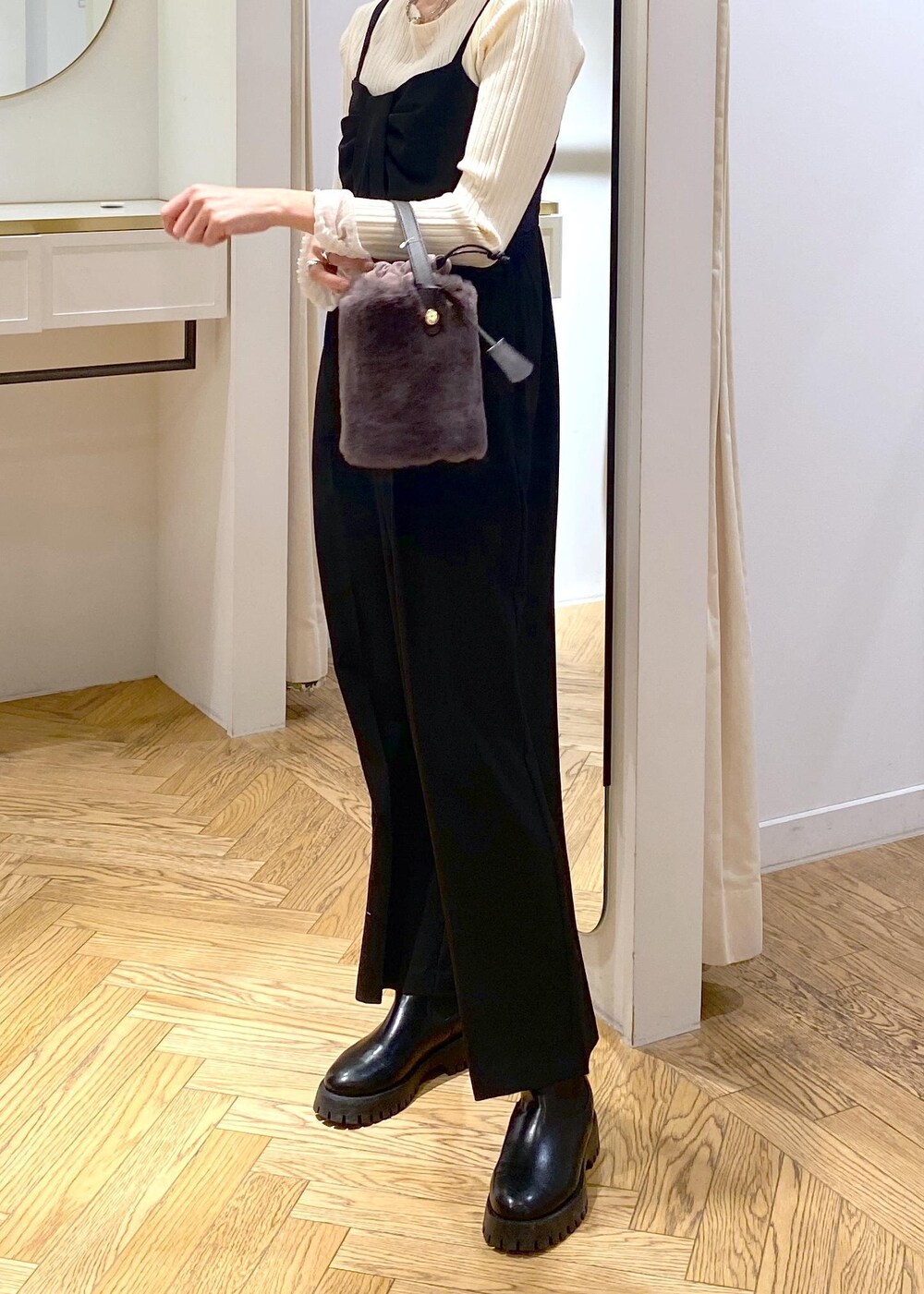 グレー系のショルダーバッグ、ブラック系のサロペット/オーバーオール、ホワイト系のニット/セーターを着用したレディースの冬コーディネートの5枚目の写真