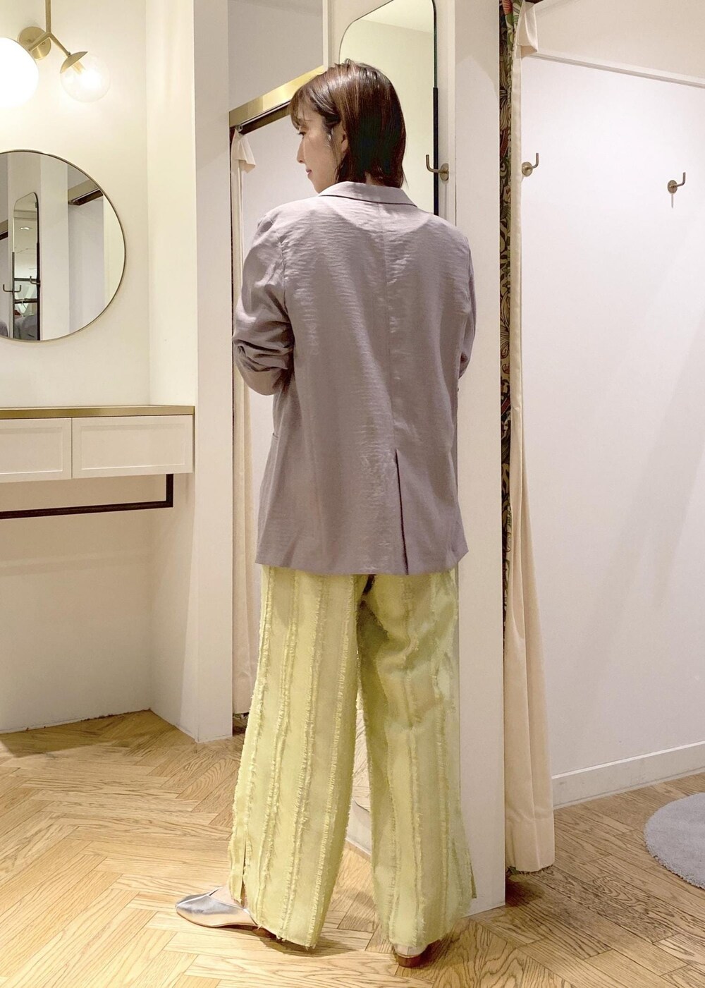 シルバー系のパンプス、グリーン系のスラックス、シルバー系のハンドバッグを着用したレディースの春コーディネートの2枚目の写真