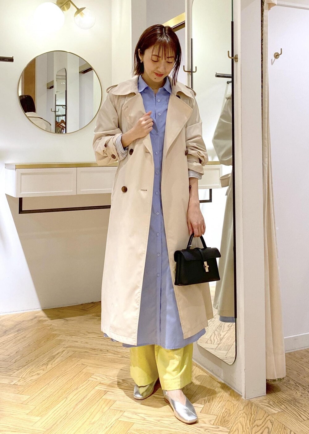 シルバー系のパンプス、ブルー系のシャツワンピース、ホワイト系のトレンチコートを着用したレディースの春コーディネートの3枚目の写真
