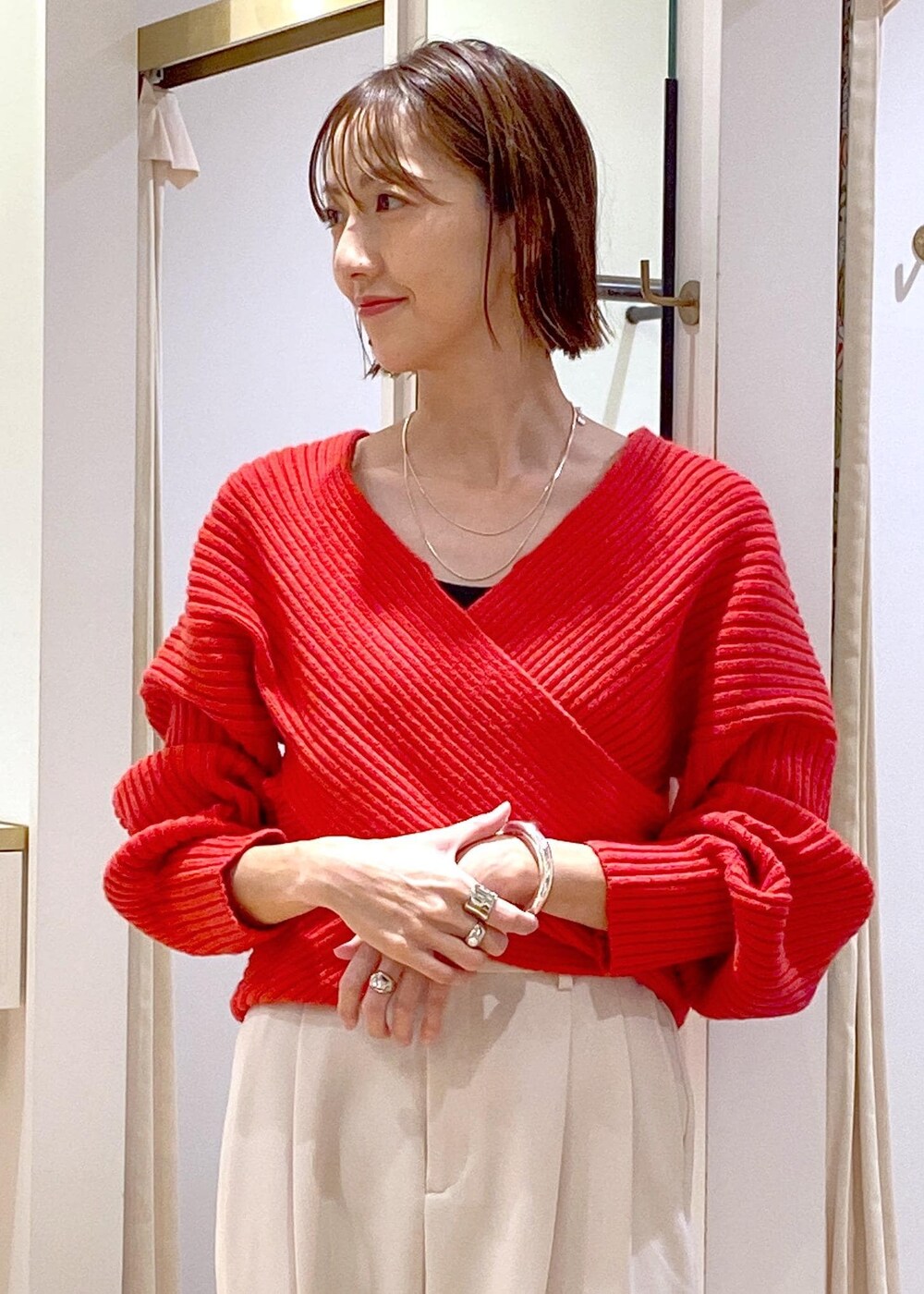 レッド系のニット/セーター、ホワイト系のスラックス、ブラック系のハンドバッグを着用したレディースの冬コーディネートの6枚目の写真