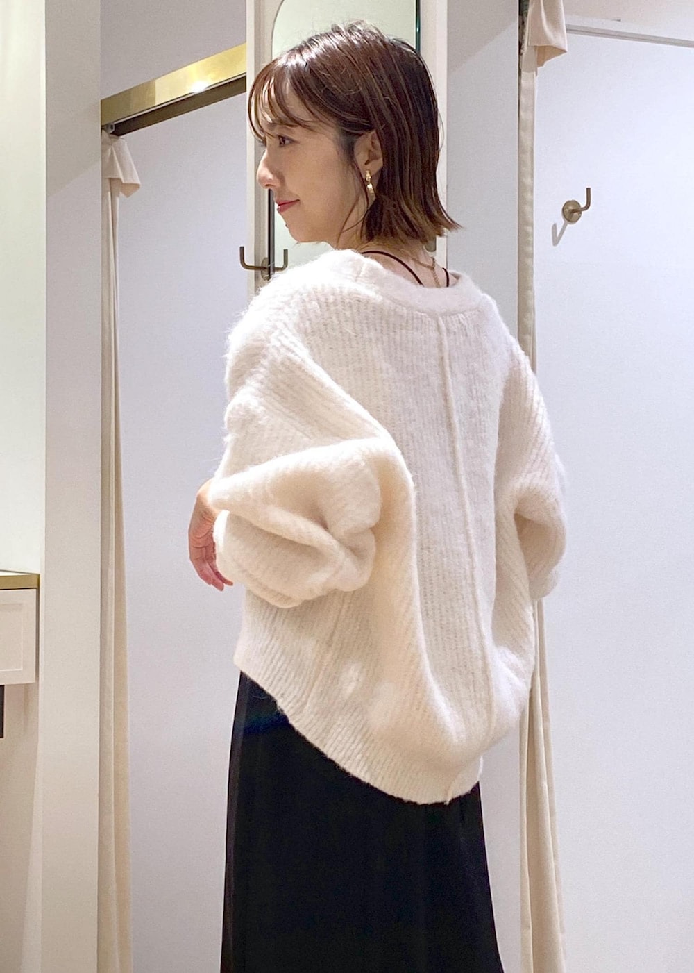 ホワイト系のブーツ、ブラック系のスカート、ブラウン系のショルダーバッグを着用したレディースの秋コーディネートの7枚目の写真