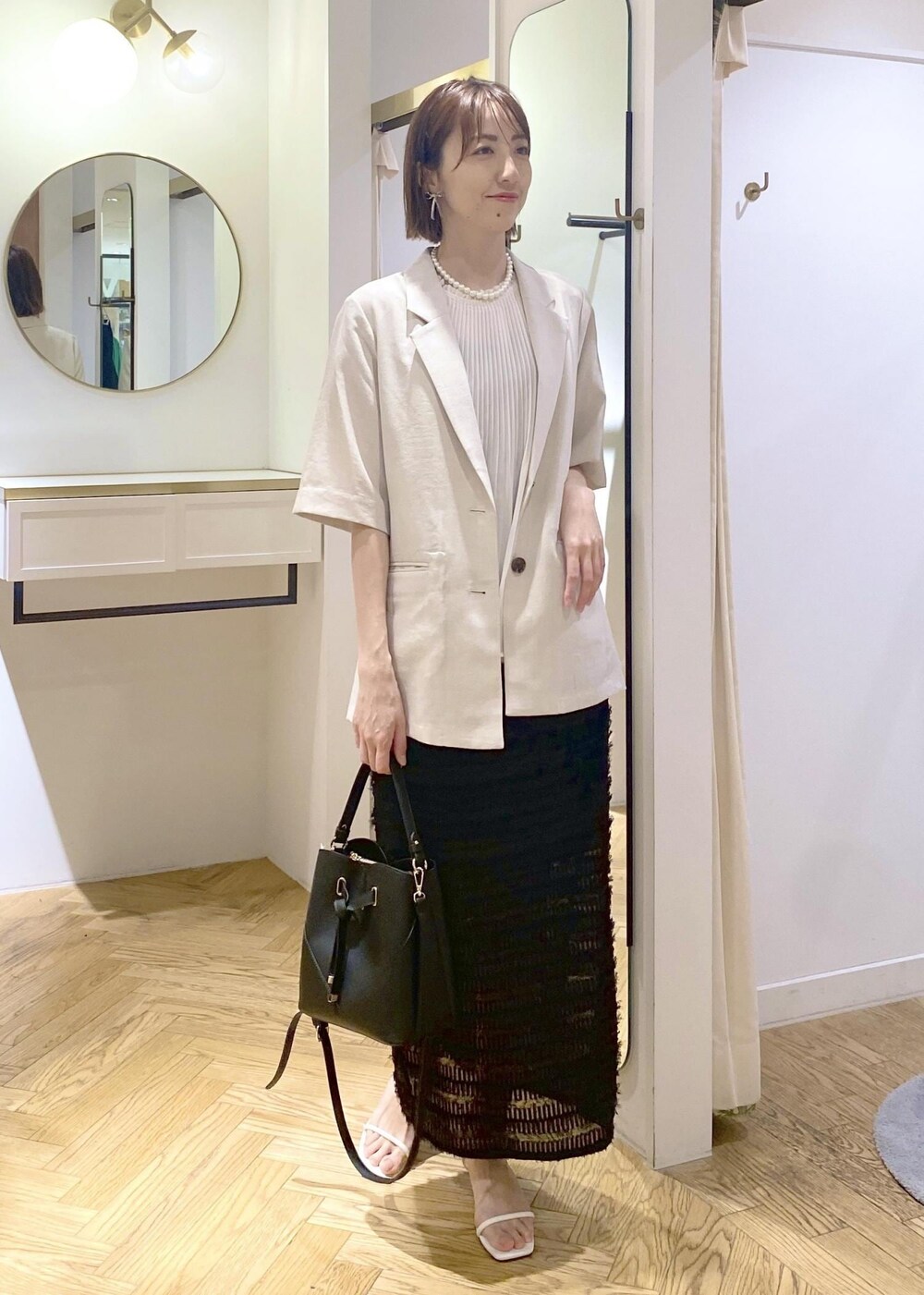 ブラック系のハンドバッグ、ホワイト系のサンダル、ホワイト系のシャツ/ブラウスを着用したレディースの春コーディネートの4枚目の写真
