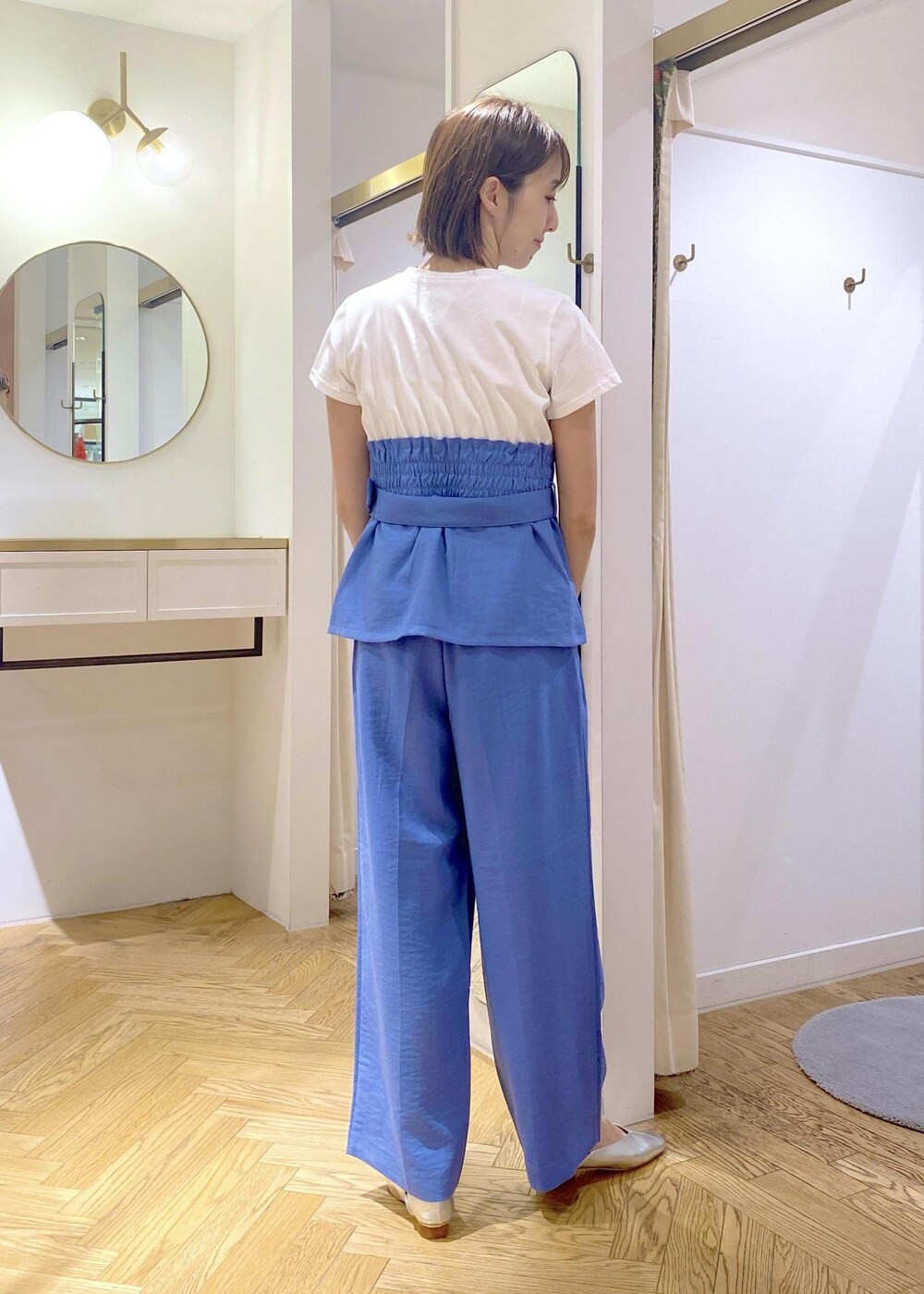 シルバー系のハンドバッグ、シルバー系のパンプス、ブルー系のTシャツ/カットソーを着用したレディースの春コーディネートの3枚目の写真