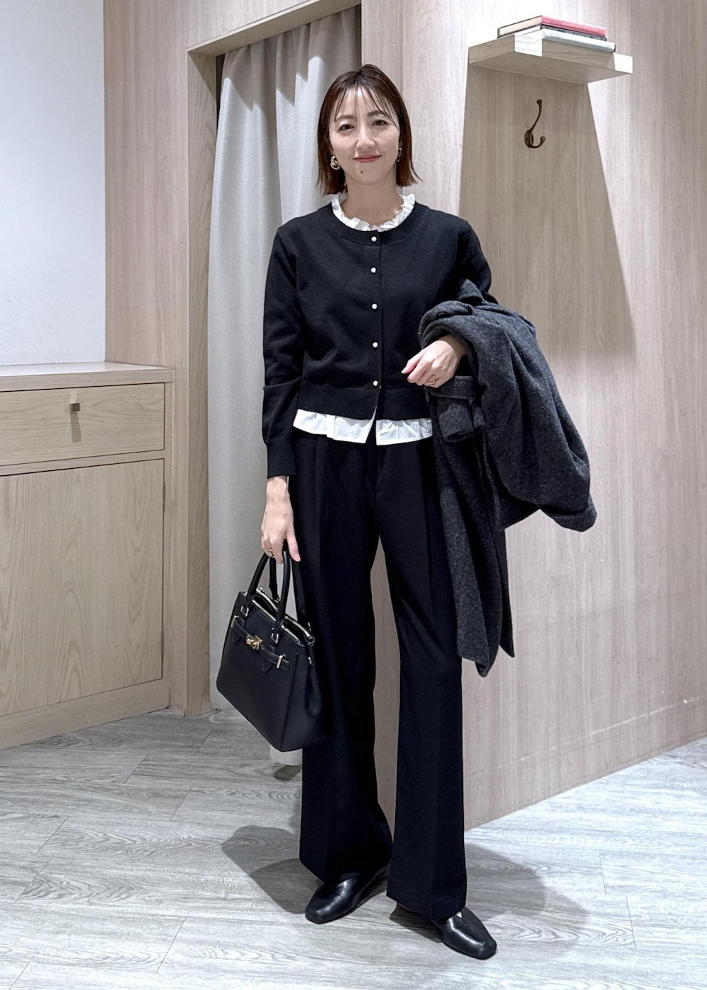 ブラック系のショルダーバッグ、ブラック系のスラックス、グレー系のその他アウターを着用したレディースの冬コーディネートの6枚目の写真