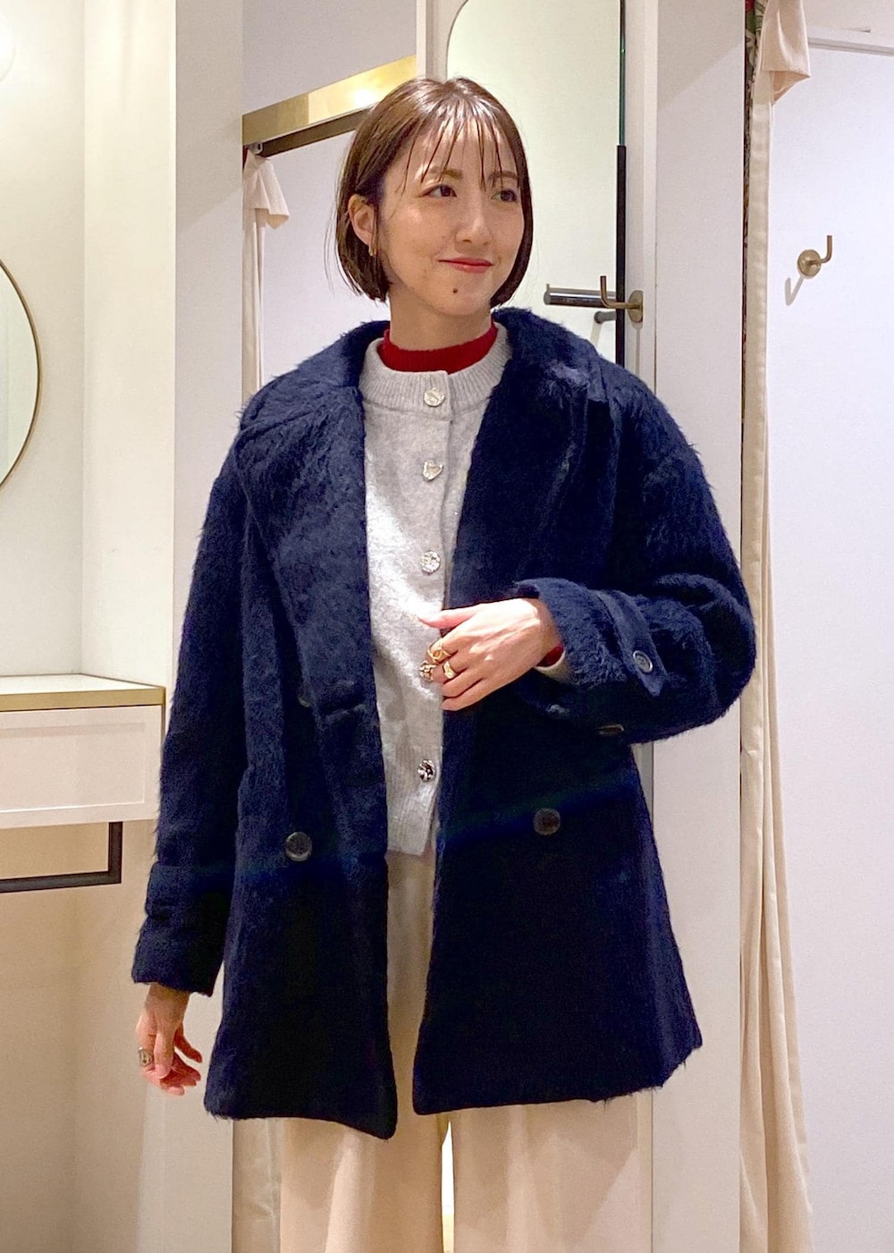 ホワイト系のブーツ、グレー系のカーディガン/ボレロ、レッド系のニット/セーターを着用したレディースの冬コーディネートの5枚目の写真