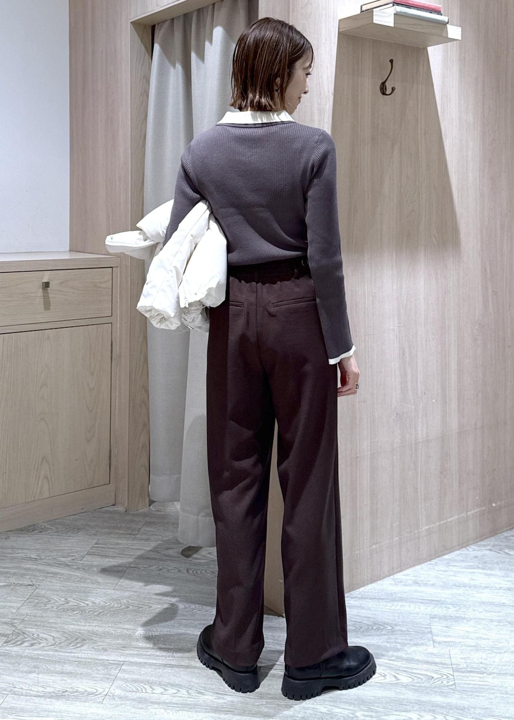 ブラウン系のスラックス、ブラック系のショルダーバッグ、ホワイト系のダウンジャケット/コートを着用したレディースの冬コーディネートの5枚目の写真