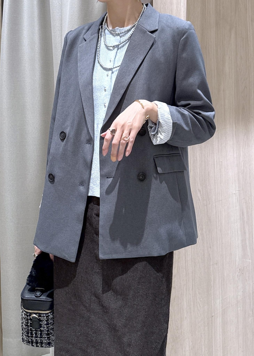 グレー系のテーラードジャケット、ブルー系のカーディガン/ボレロ、ブラウン系のスカートを着用したレディースの秋コーディネートの6枚目の写真
