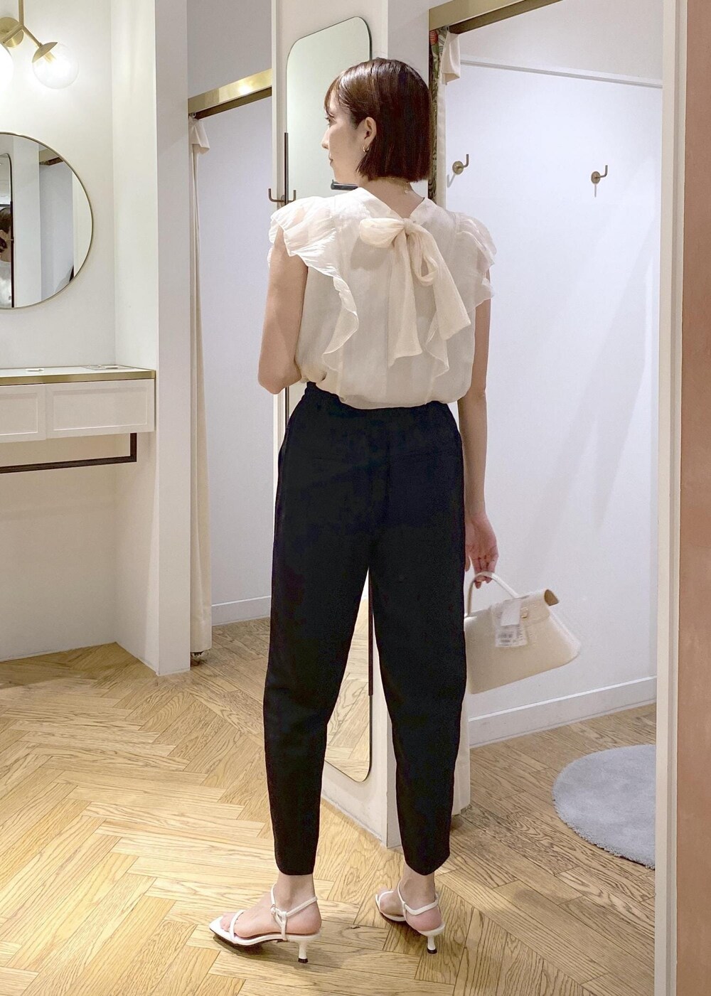 ブラック系のキャミソール、ホワイト系のショルダーバッグ、ブラック系のスラックスを着用したレディースの夏コーディネートの2枚目の写真