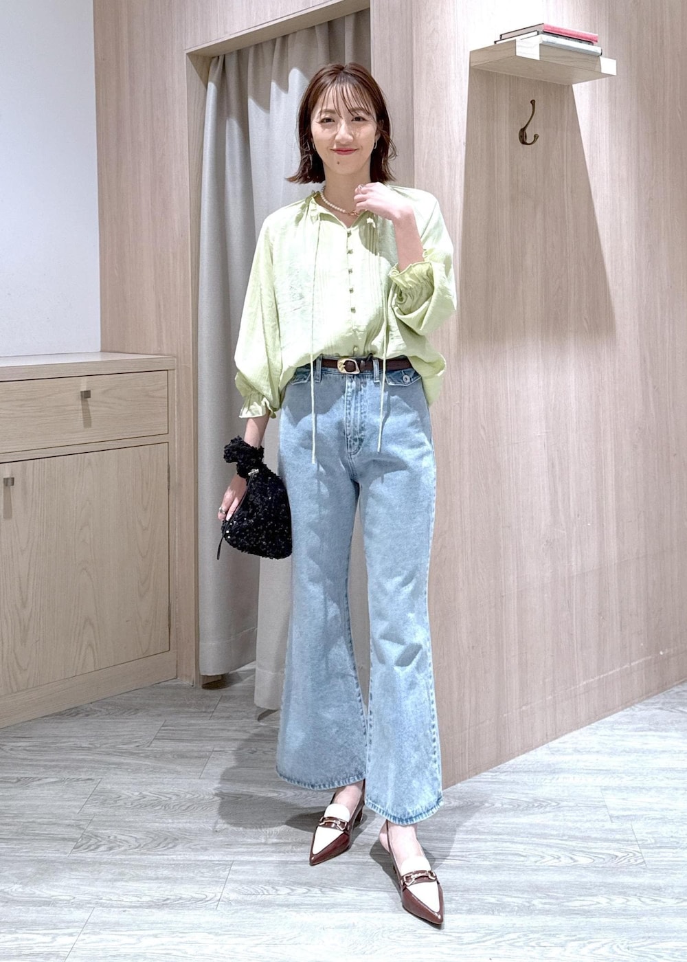 ブルー系のデニムパンツ、ブラウン系のパンプス、ブラック系のハンドバッグを着用したレディースの春コーディネートの10枚目の写真