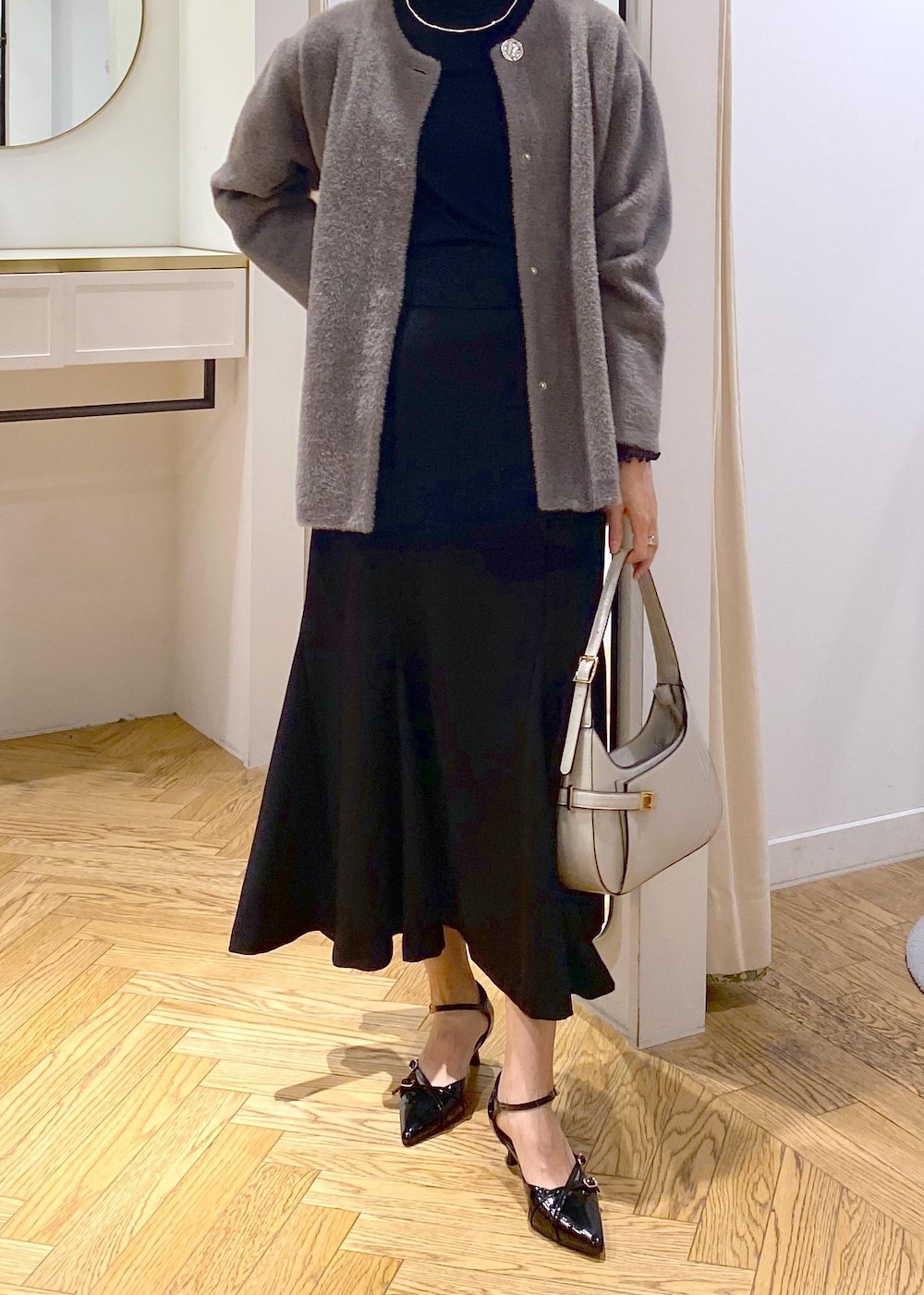 ブラック系のパンプス、ブラック系のスカート、ブラウン系のその他アウターを着用したレディースの秋コーディネートの4枚目の写真