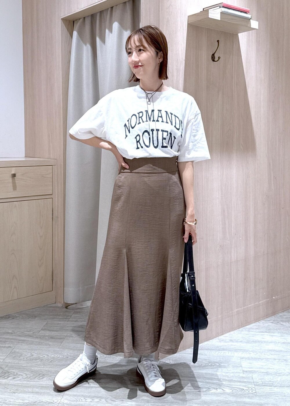 グリーン系のスカート、ホワイト系のTシャツ/カットソー、ブラック系のハンドバッグを着用したレディースの春コーディネートの5枚目の写真