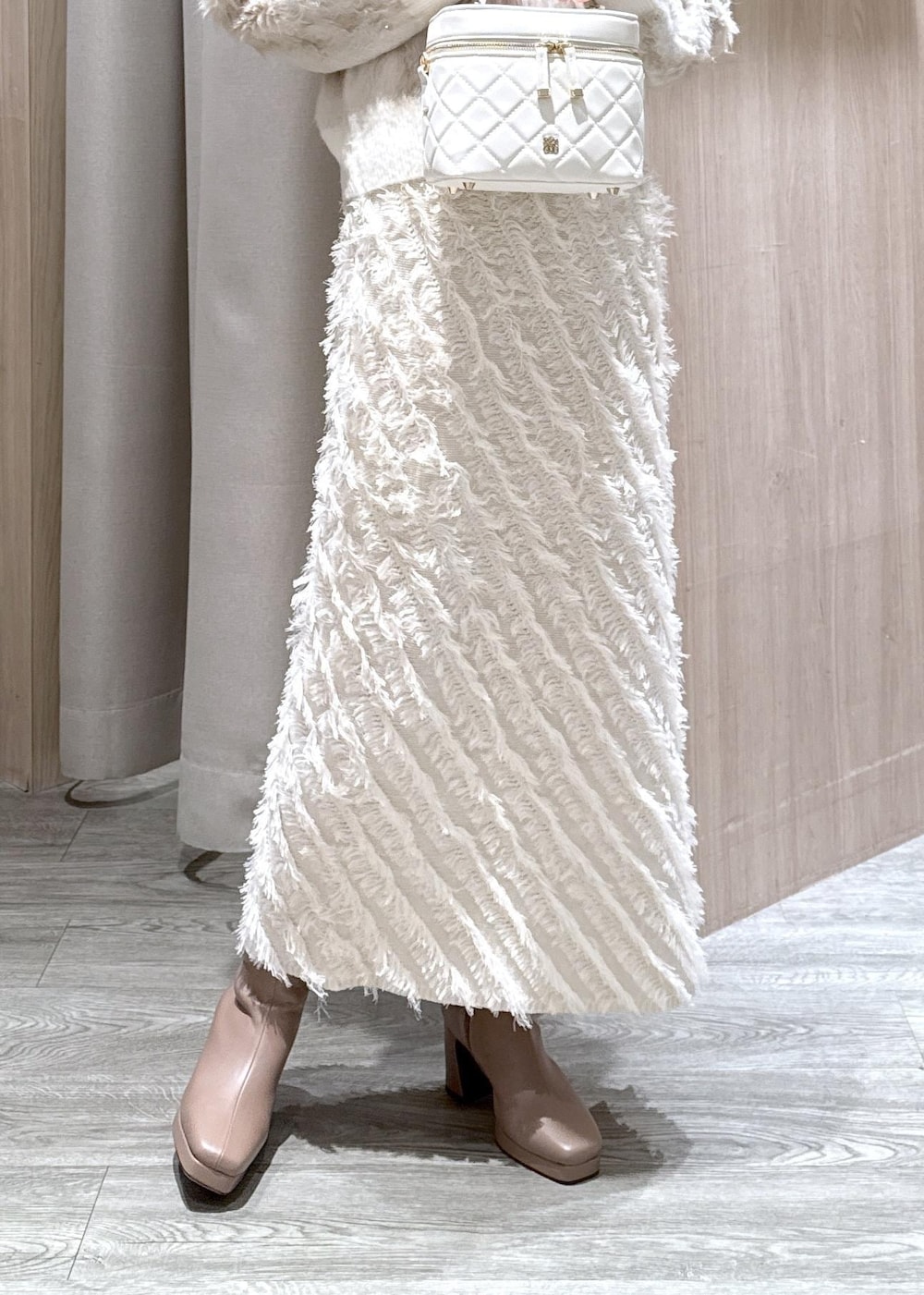 ホワイト系のスカート、ベージュ系のブーツ、ホワイト系のハンドバッグを着用したレディースの秋コーディネートの10枚目の写真