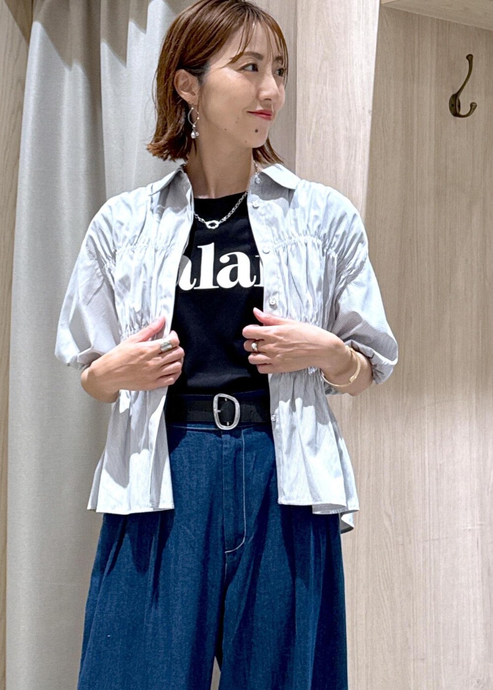 ブラック系のショルダーバッグ、ブラック系のサンダル、ブルー系のデニムパンツを着用したレディースの夏コーディネートの9枚目の写真