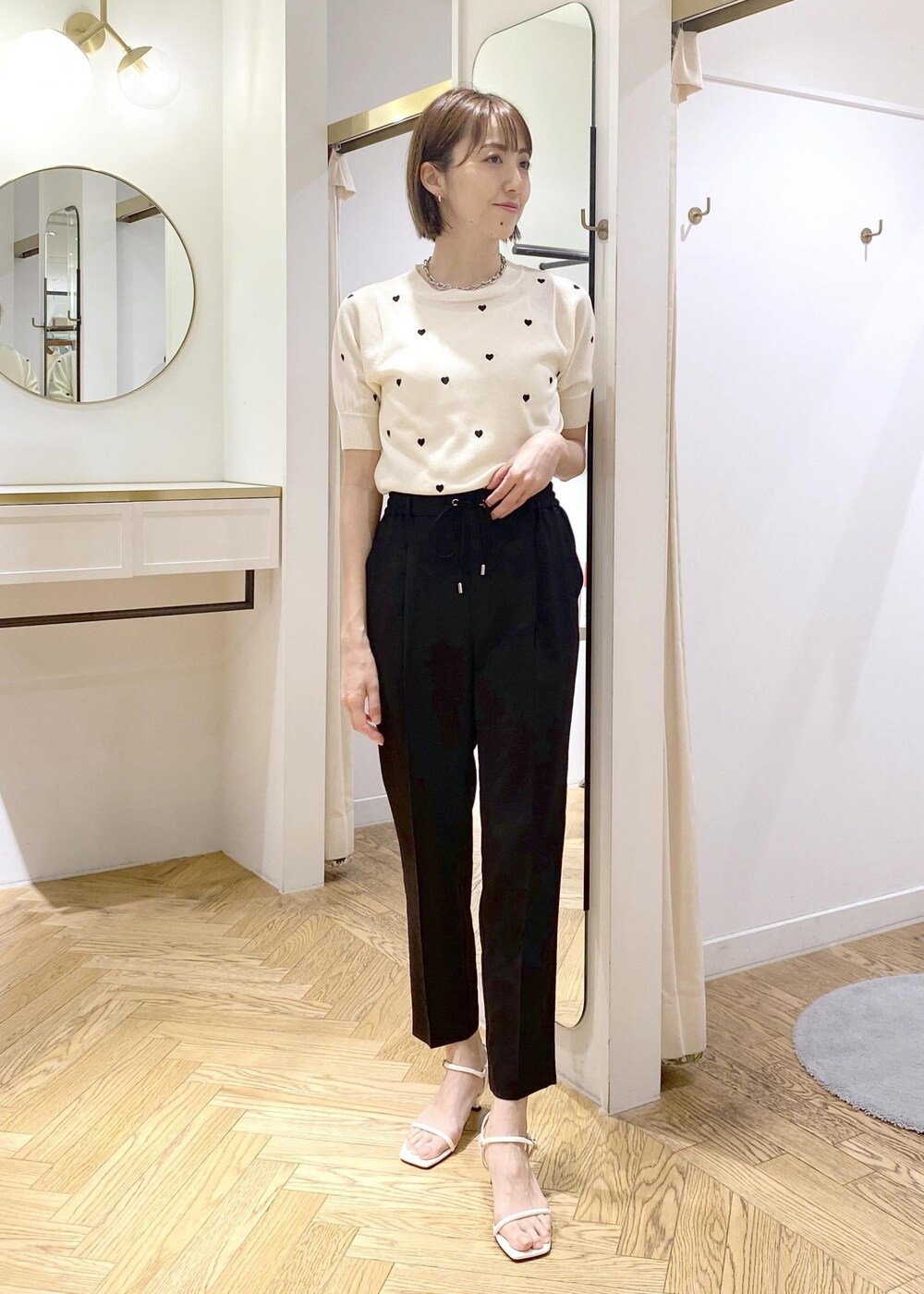 ブラック系のショルダーバッグ、ホワイト系のキャミソール、ブラック系のスラックスを着用したレディースの春コーディネートの5枚目の写真