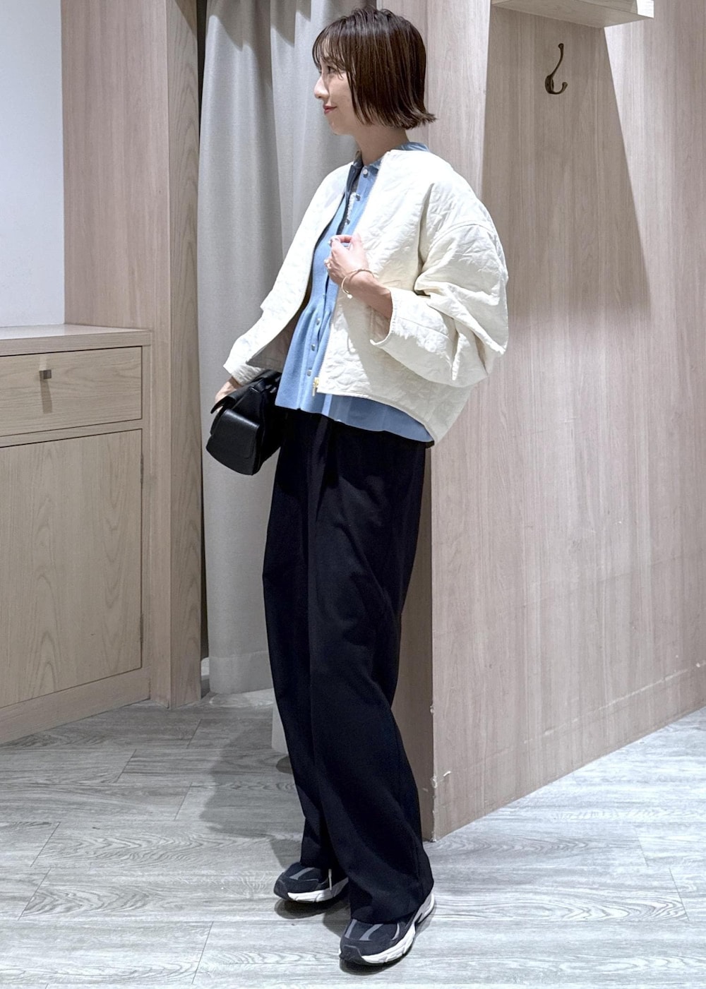 ブラック系のスラックス、ブラック系のショルダーバッグ、ブルー系のカーディガン/ボレロを着用したレディースの秋コーディネートの3枚目の写真