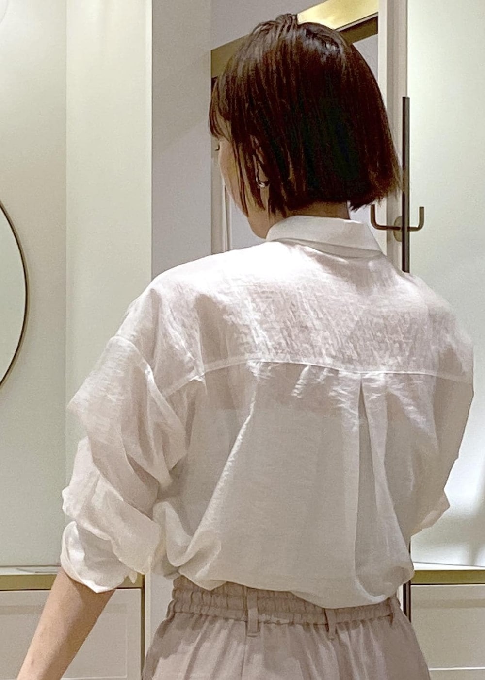 ブラック系のパンプス、ブラック系のハンドバッグ、ホワイト系のスラックスを着用したレディースの夏コーディネートの7枚目の写真