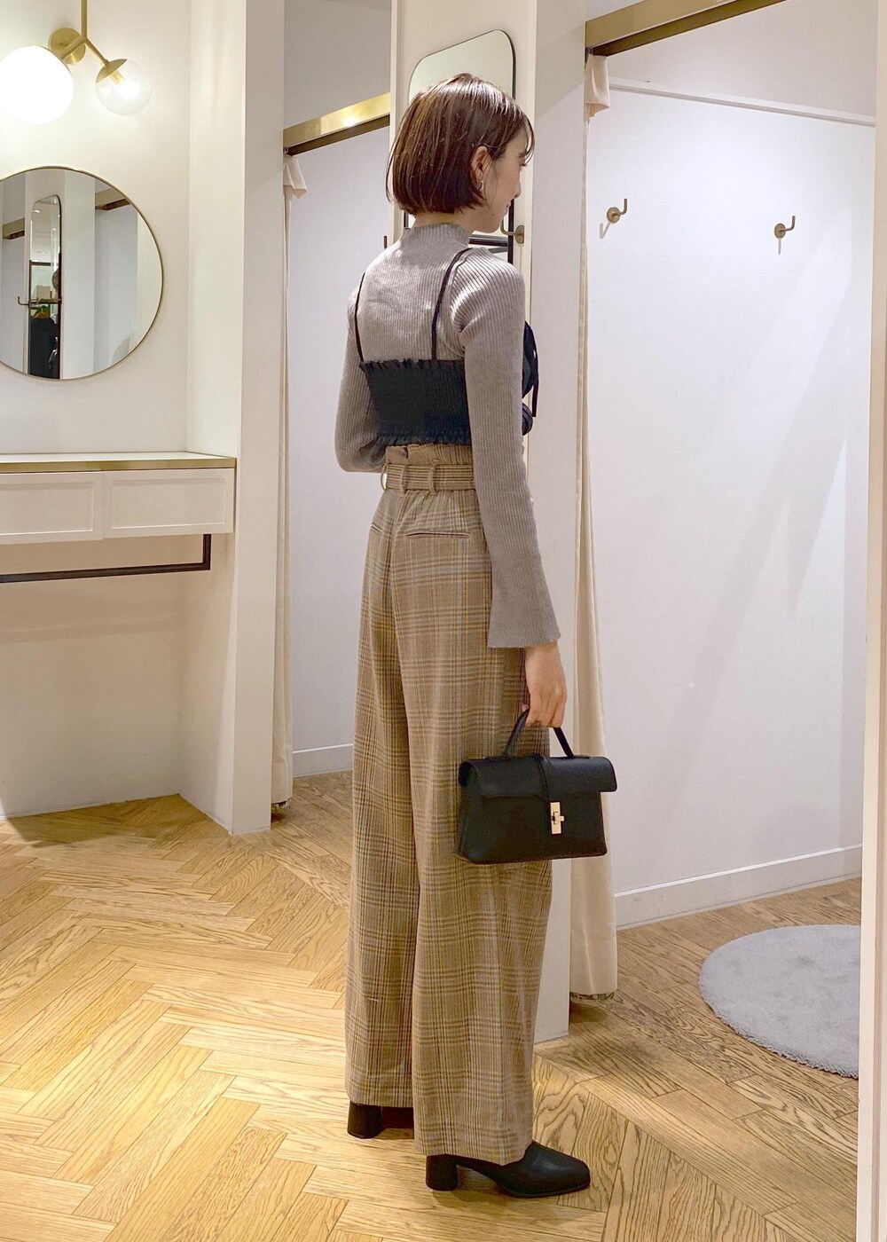 ブラック系のショルダーバッグ、ブラック系のブーツ、ベージュ系のスラックスを着用したレディースの秋コーディネートの3枚目の写真