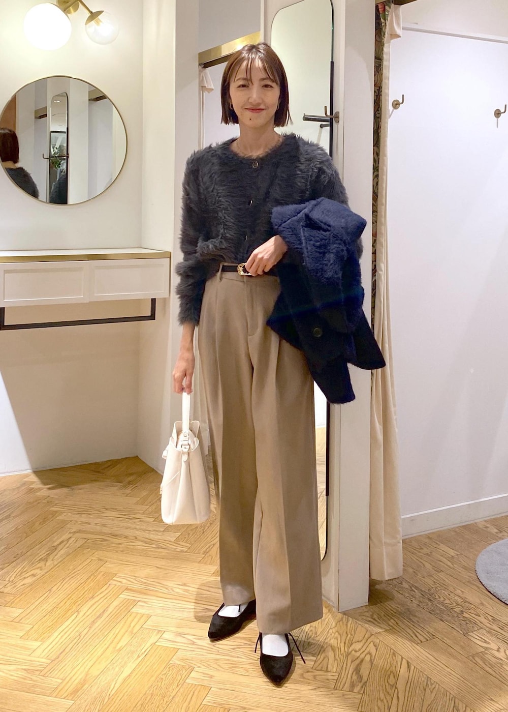 ホワイト系のショルダーバッグ、ベージュ系のスラックス、グレー系のカーディガン/ボレロを着用したレディースの冬コーディネートの8枚目の写真