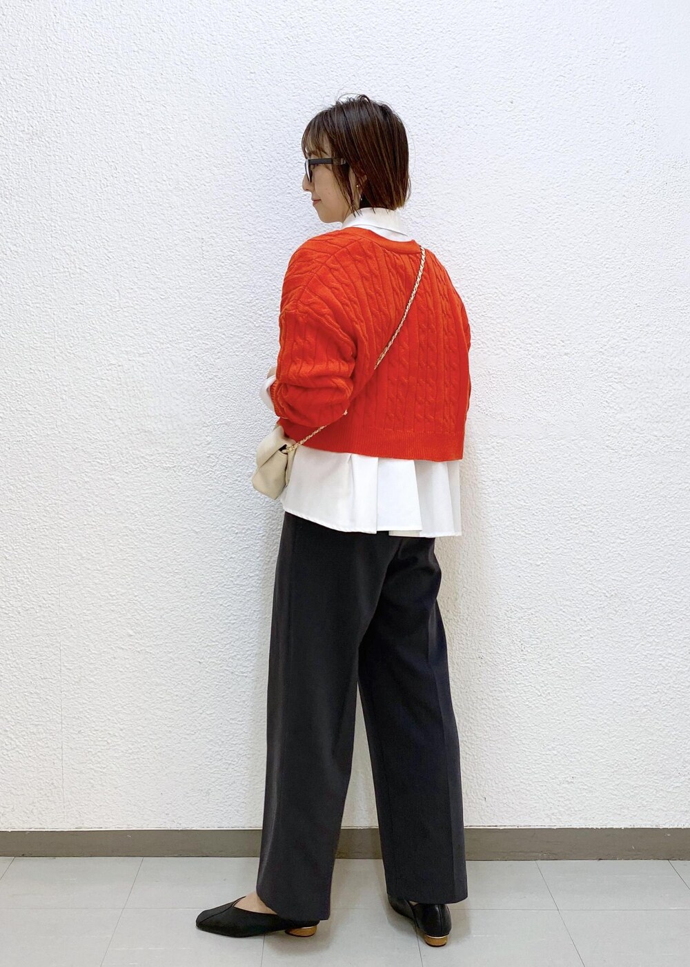 グレー系のスラックス、ホワイト系のシャツ/ブラウス、オレンジ系のカーディガン/ボレロを着用したレディースの冬コーディネートの2枚目の写真