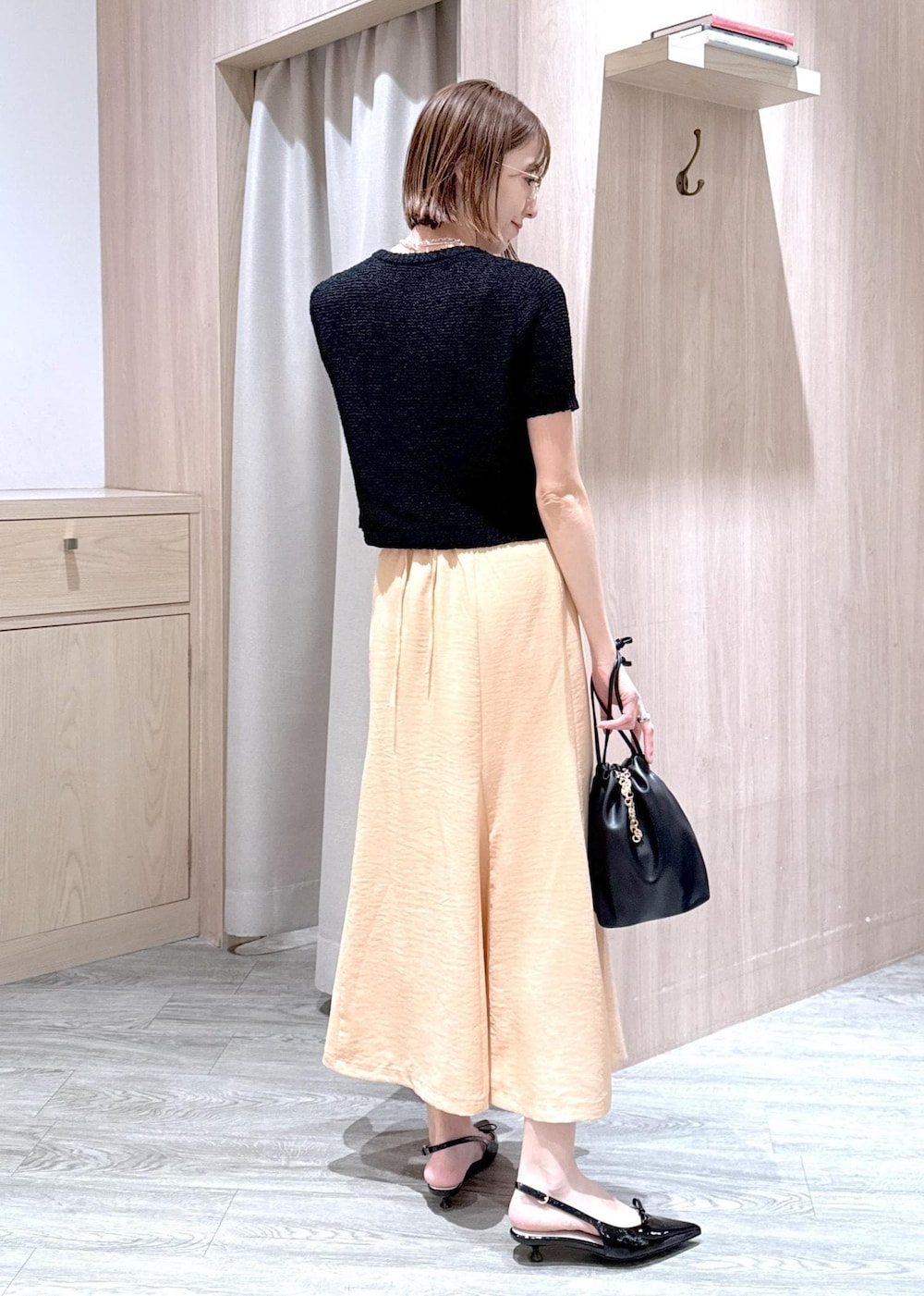 ブラック系のパンプス、オレンジ系のスカート、ブラック系のハンドバッグを着用したレディースの春コーディネートの5枚目の写真