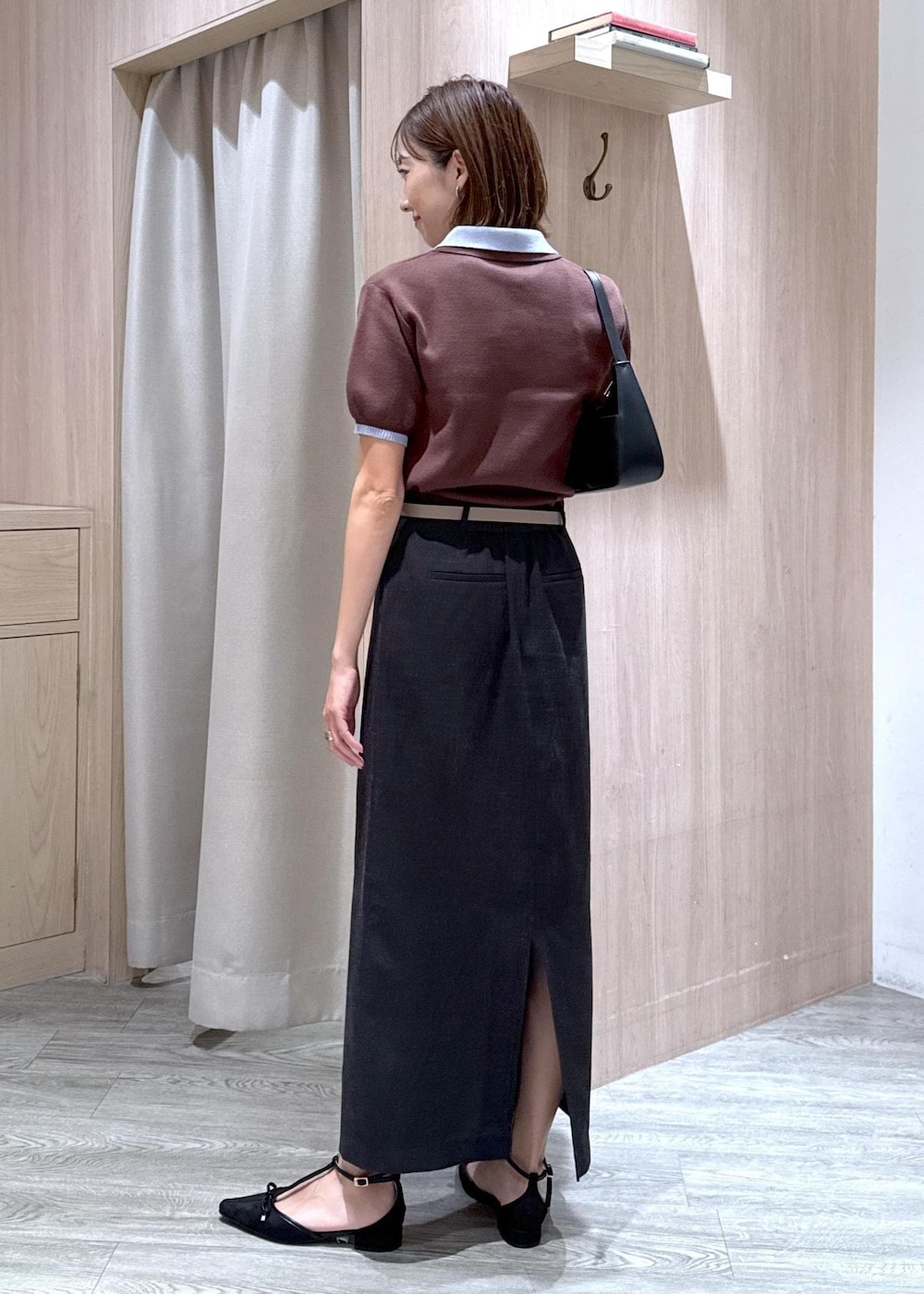 ブラック系のハンドバッグ、グレー系のスカート、ブラック系のパンプスを着用したレディースの夏コーディネートの3枚目の写真