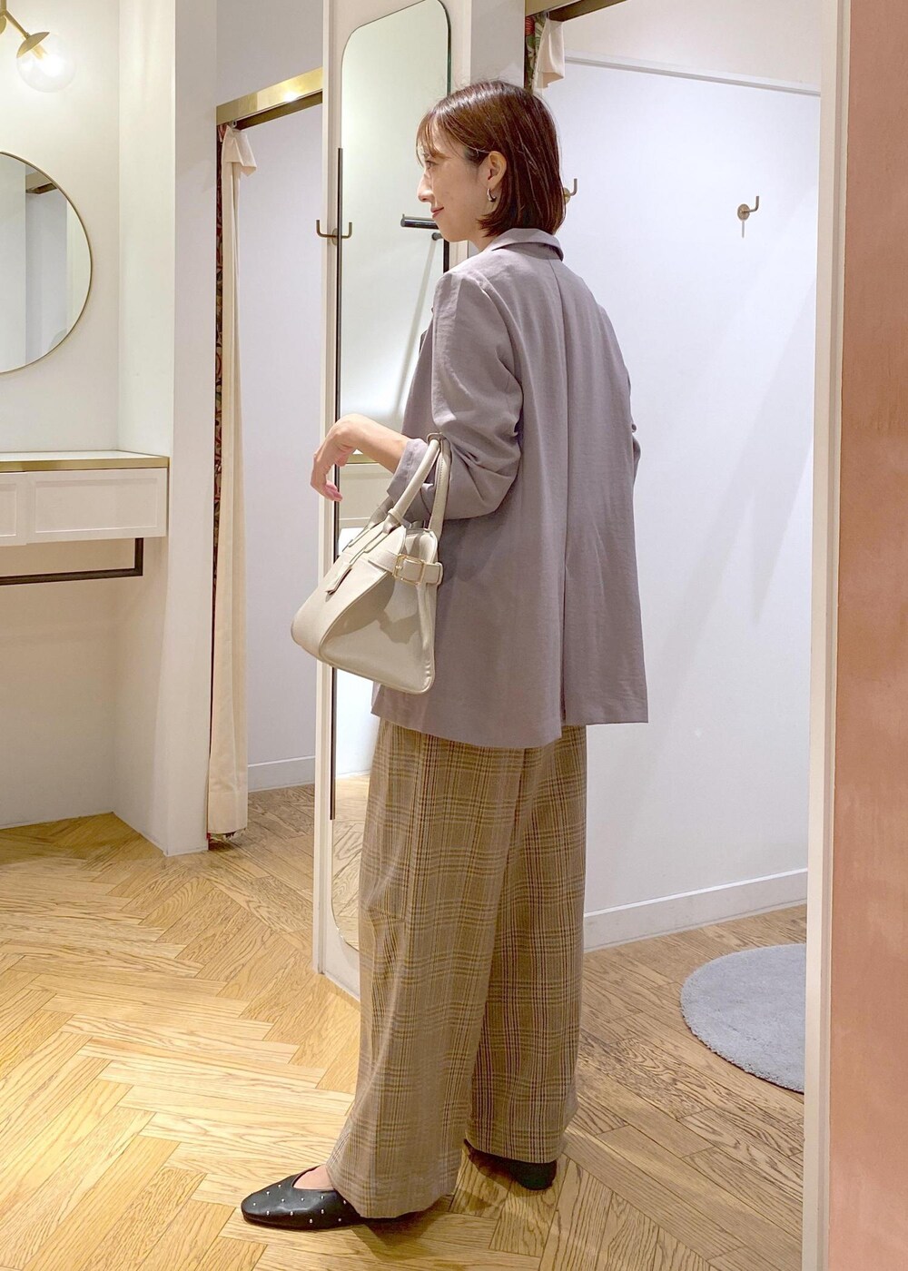 グレー系のテーラードジャケット、ブラック系のバレエシューズ、ベージュ系のトートバッグを着用したレディースの秋コーディネートの2枚目の写真