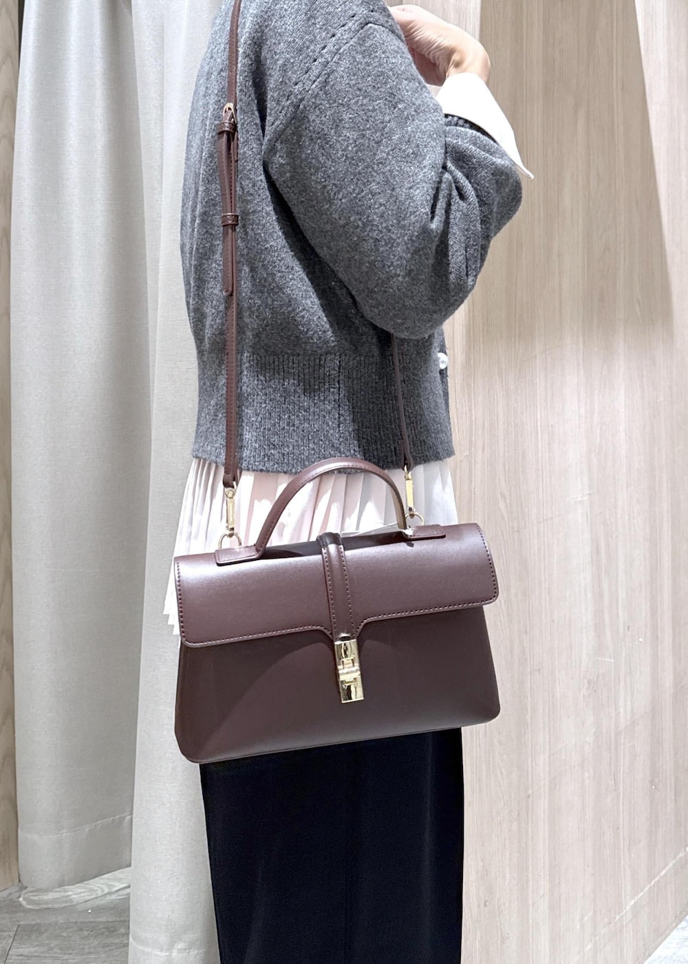 ブラウン系のショルダーバッグ、ブラック系のスラックス、グレー系のカーディガン/ボレロを着用したレディースの秋コーディネートの7枚目の写真