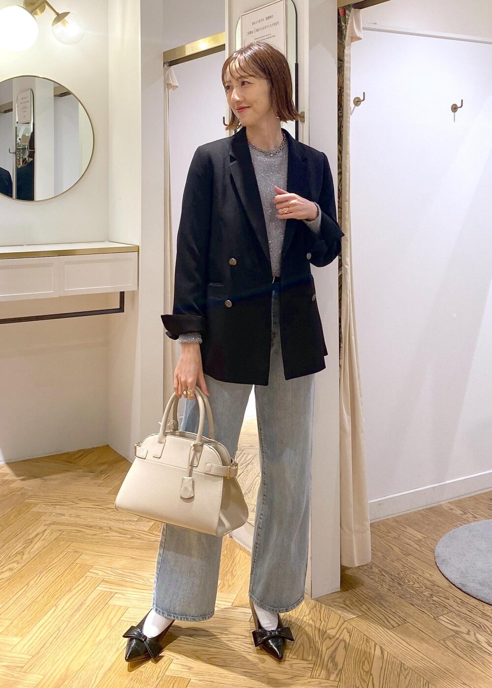 ブラック系のパンプス、グレー系のニット/セーター、ブルー系のデニムパンツを着用したレディースの冬コーディネートの2枚目の写真