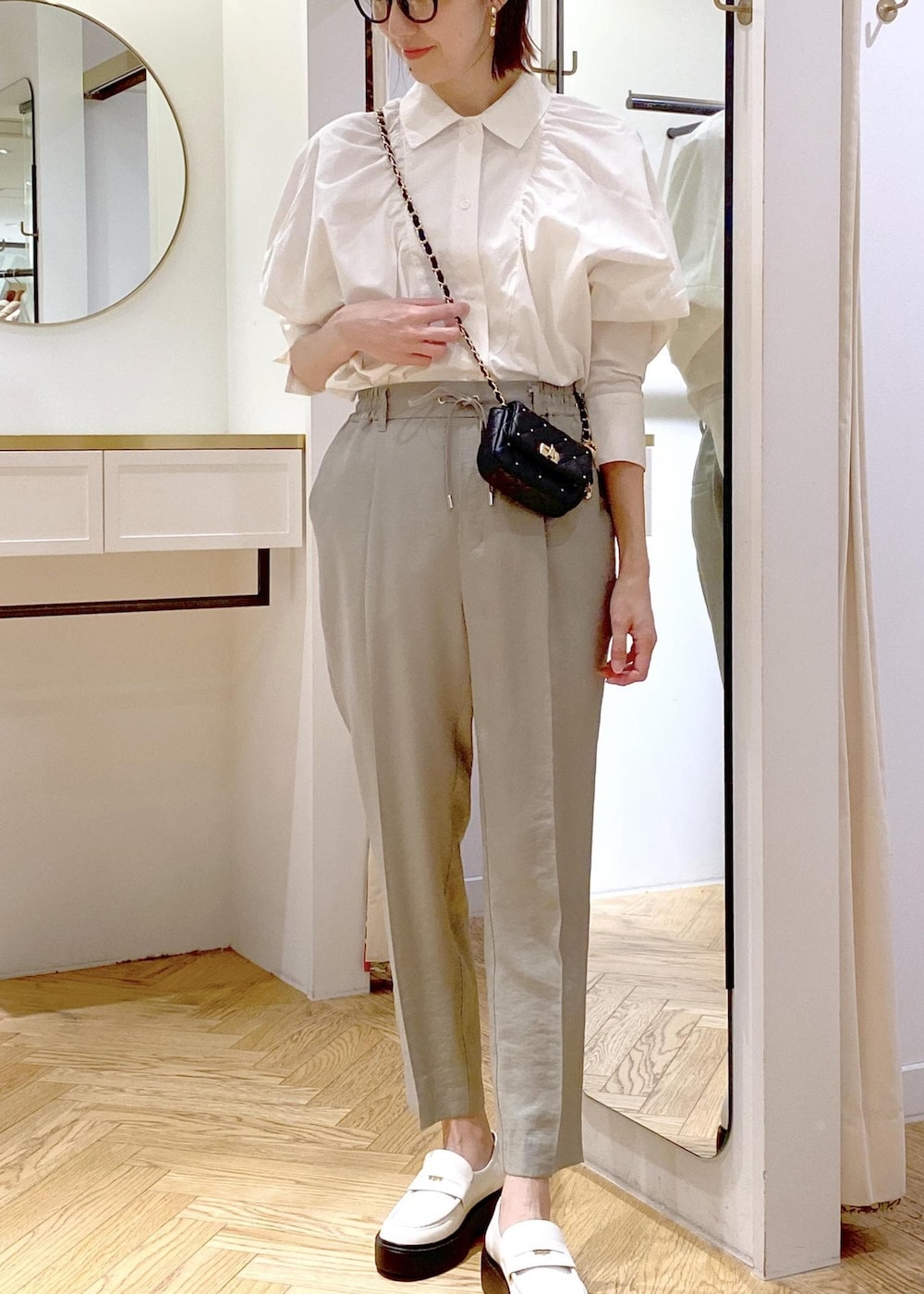 ブラック系のショルダーバッグ、ホワイト系のローファー、グリーン系のスラックスを着用したレディースの春コーディネートの3枚目の写真