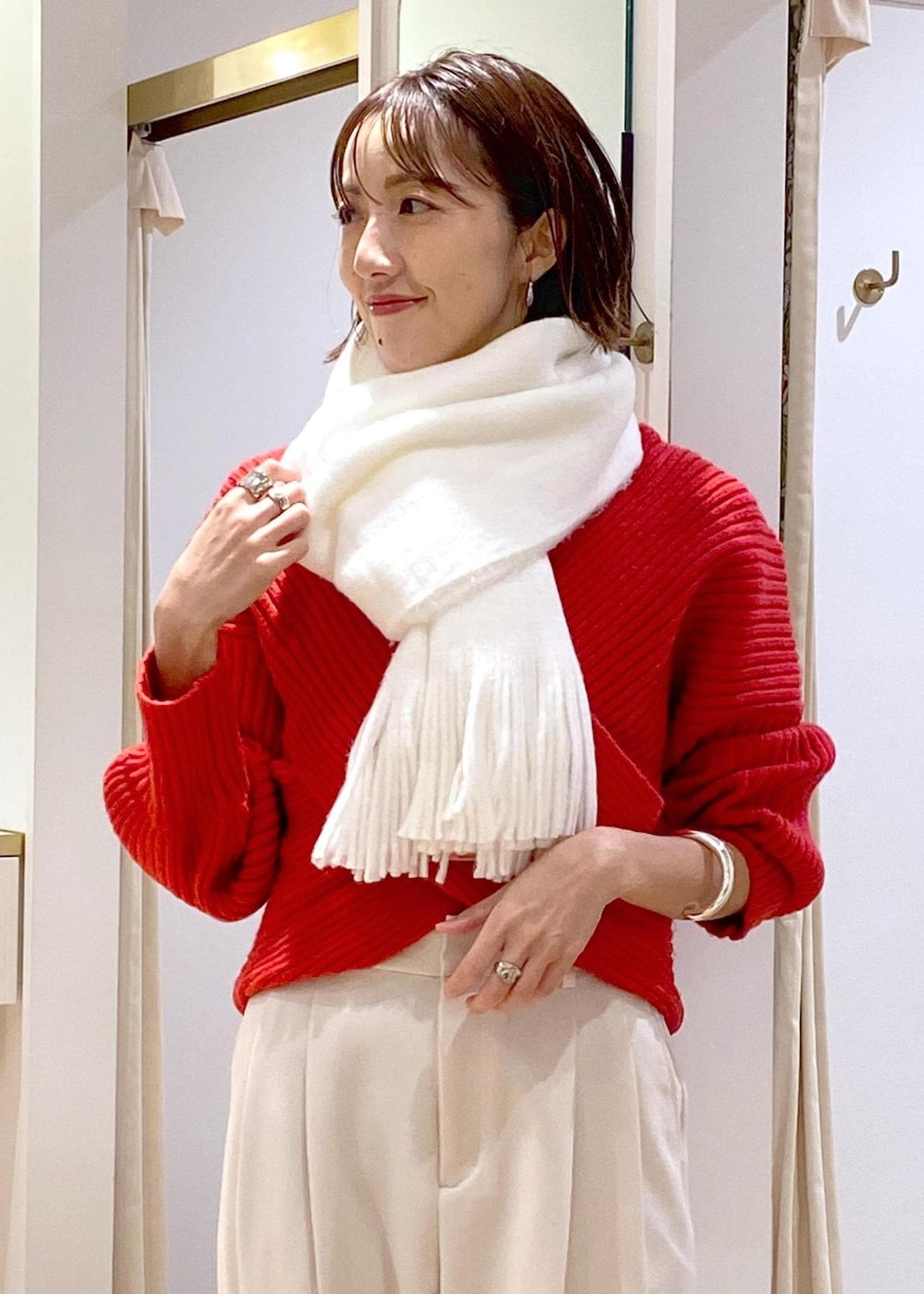 レッド系のニット/セーター、ホワイト系のスラックス、ブラック系のショルダーバッグを着用したレディースの冬コーディネートの6枚目の写真